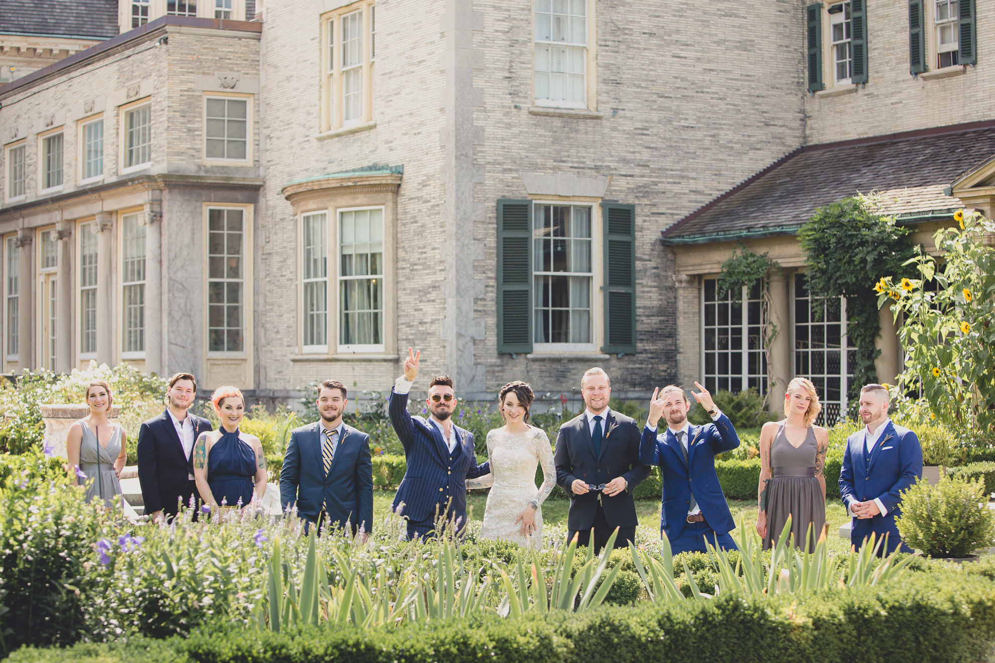 wedding party poses for photographer before garden wedding ceremony at the George Eastman House in Rochester, NY 