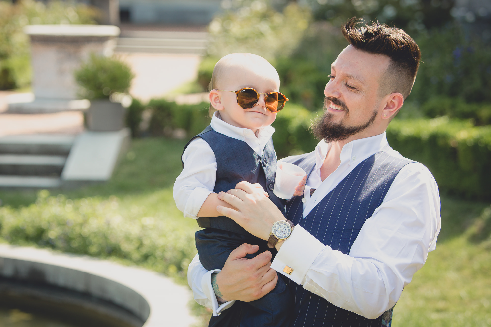 groom and son pose for photographer before garden wedding ceremony at the George Eastman House in Rochester, NY 