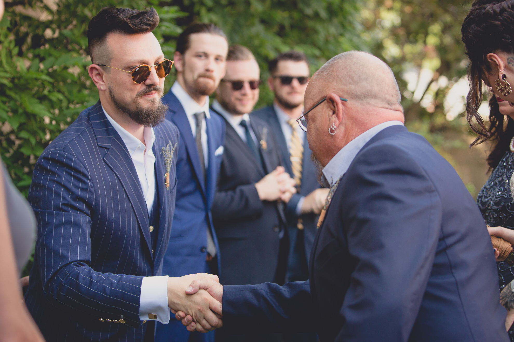 groom shakes fathers hand during garden wedding ceremony at the George Eastman House in Rochester, NY 