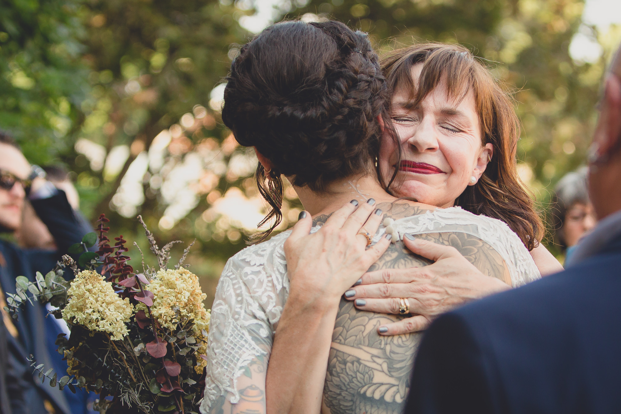 mom hugs bride bride during garden wedding ceremony at the George Eastman House in Rochester, NY 