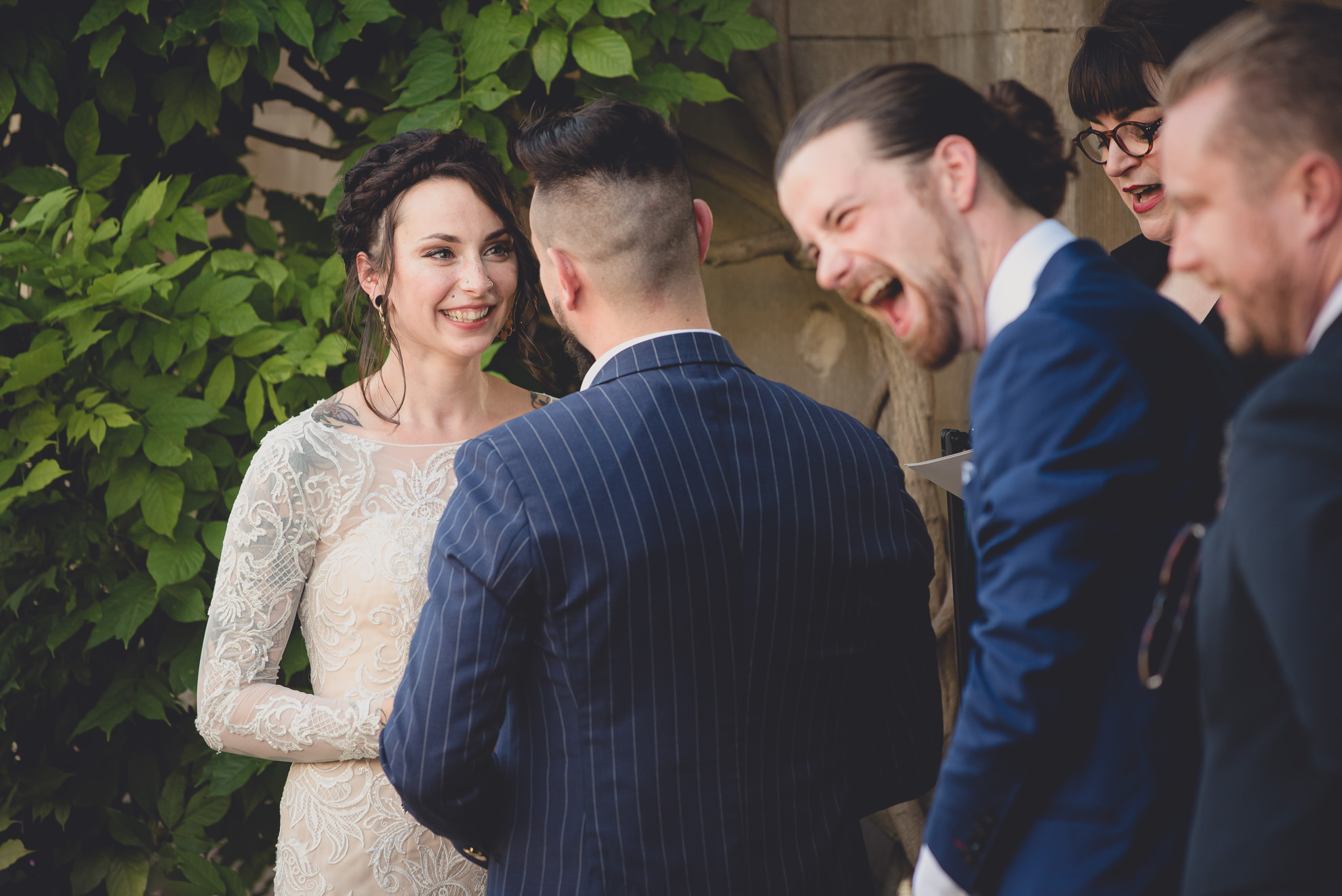 best man laughs during reading during garden wedding ceremony at the George Eastman House in Rochester, NY 