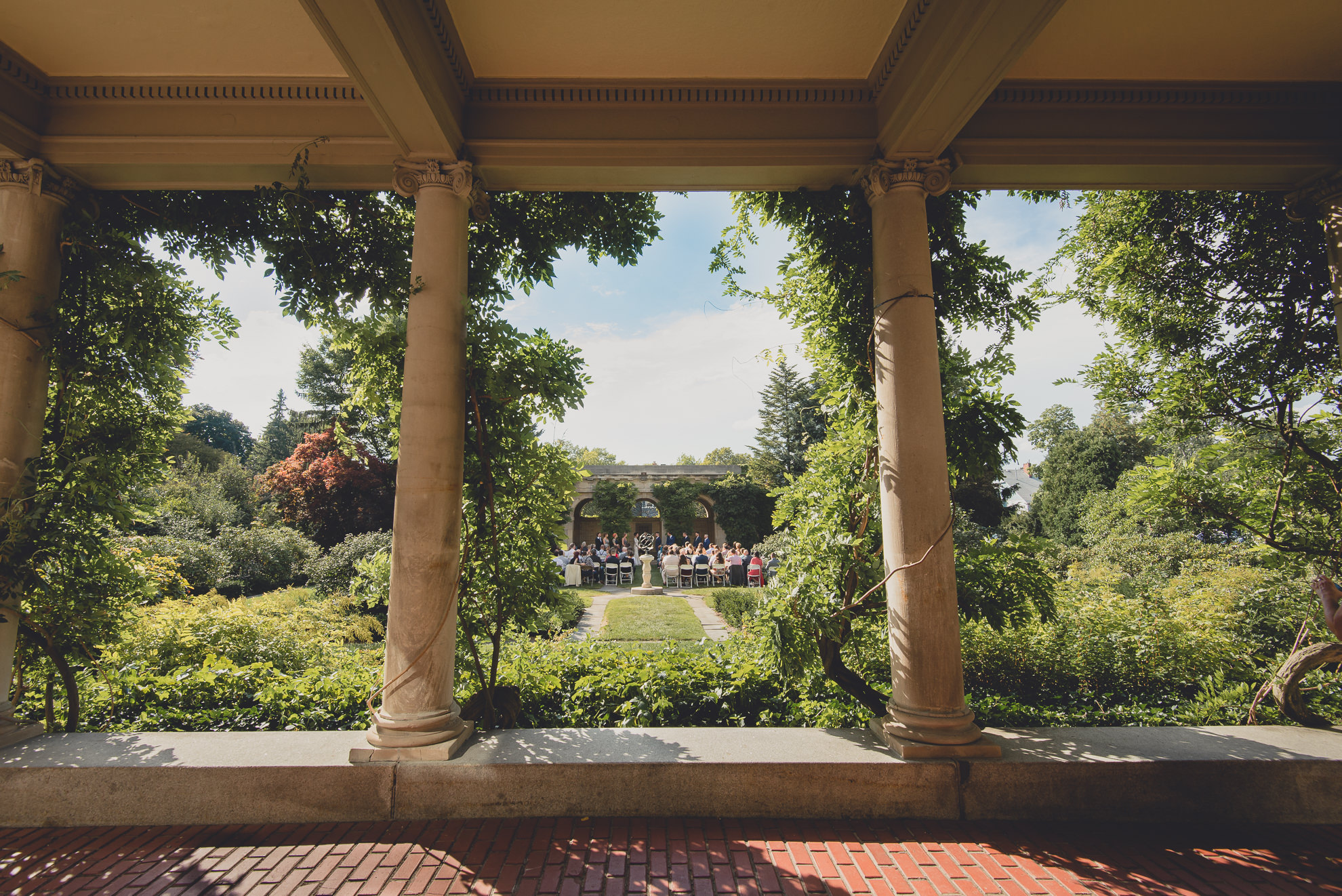 garden wedding ceremony at the George Eastman House in Rochester, NY viewed through columns