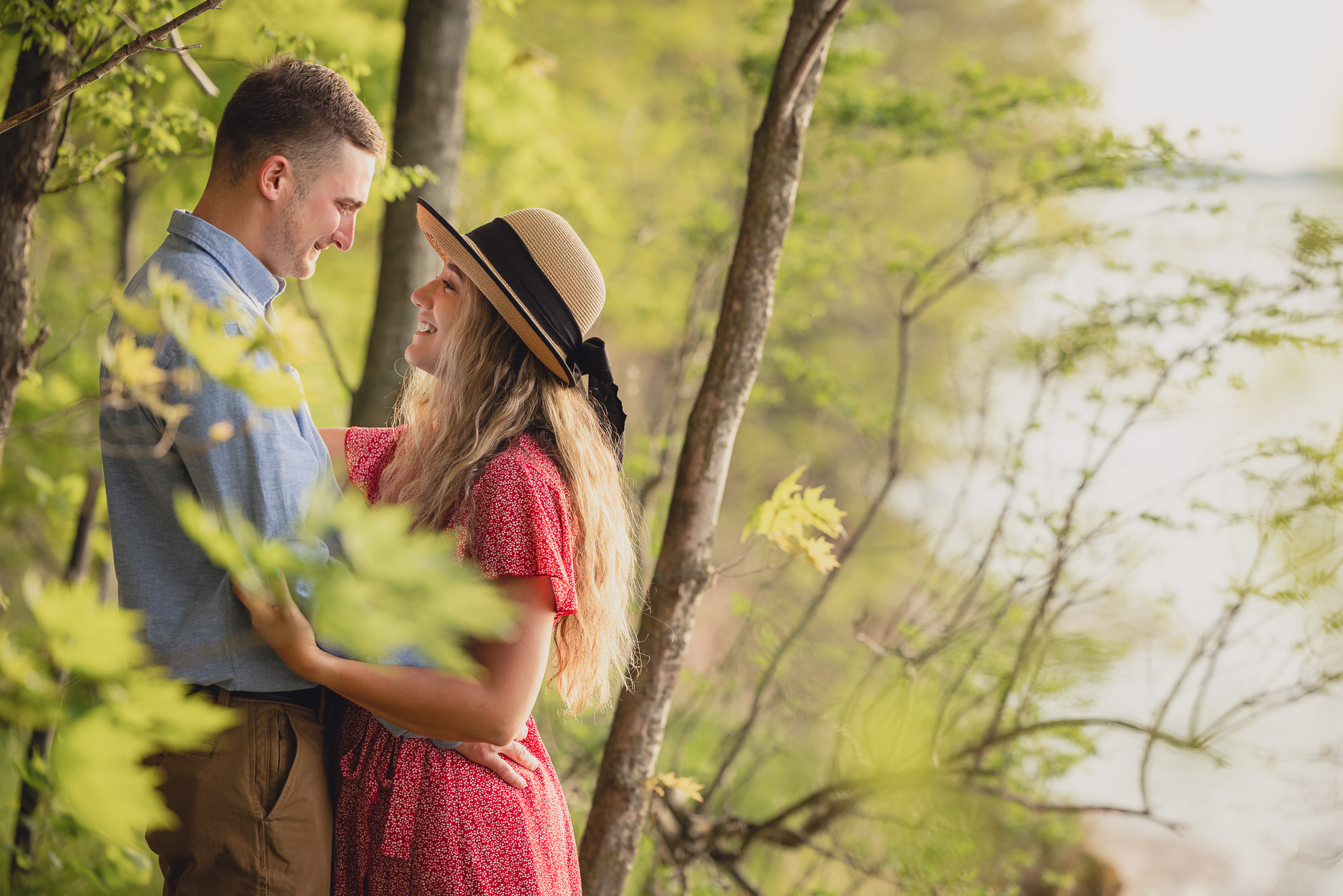 couple smiles at each other during wedding engagement proposal photography in woods by Lake Ontario Beach in Niagara County