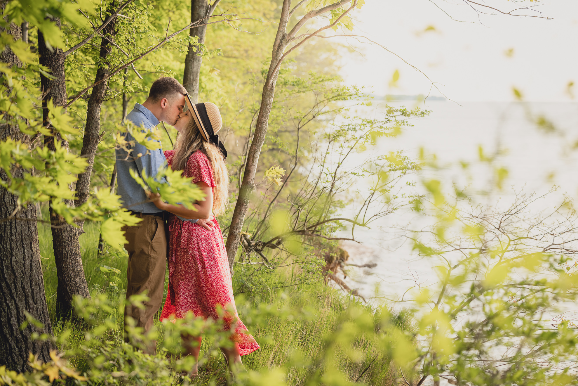 couple kisses during wedding engagement proposal photography in woods by Lake Ontario Beach in Niagara County
