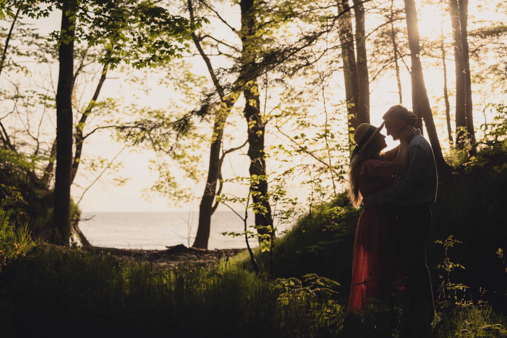 couple looks at each other during wedding engagement proposal photography in woods by Lake Ontario Beach in Niagara County