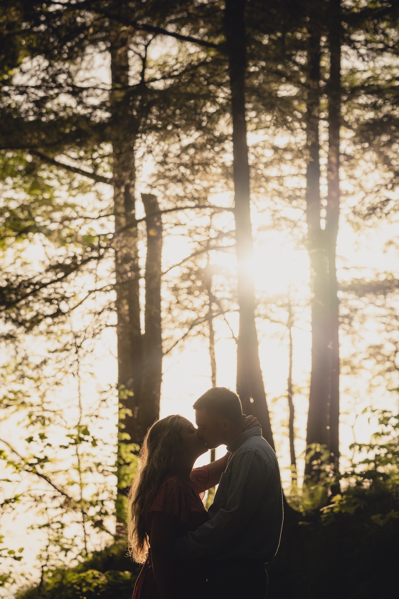 couple kisses at each other during wedding engagement proposal photography in woods by Lake Ontario Beach in Niagara County
