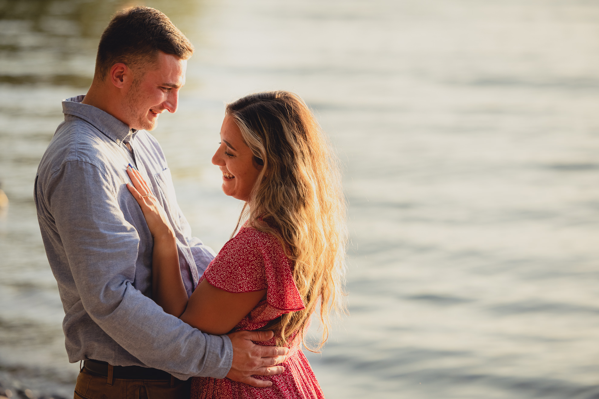 couple laughs during proposal on Lake Ontario beach at sunset during wedding engagement proposal photography in Niagara County