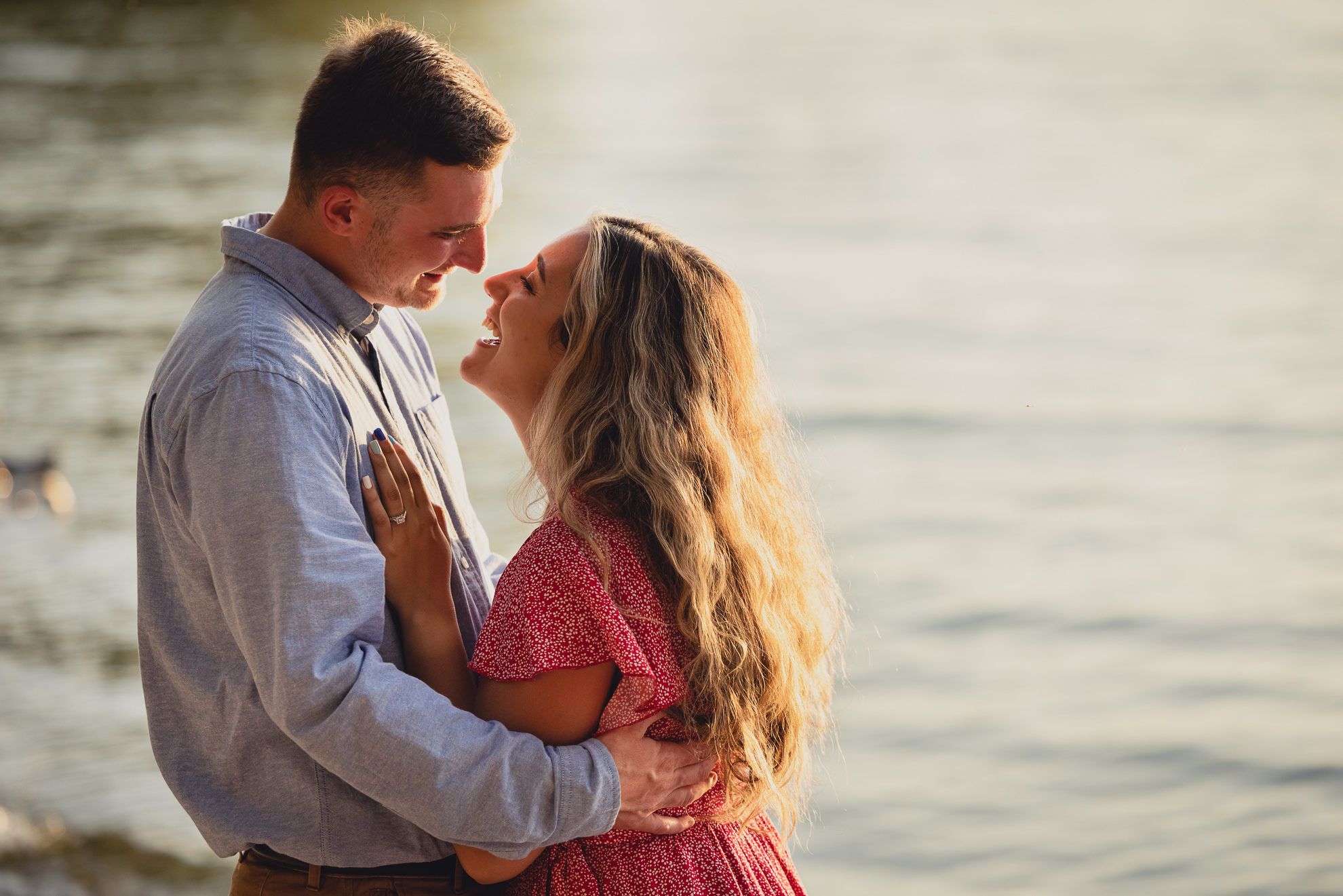 couple laughs during proposal on Lake Ontario beach at sunset during wedding engagement proposal photography in Niagara County