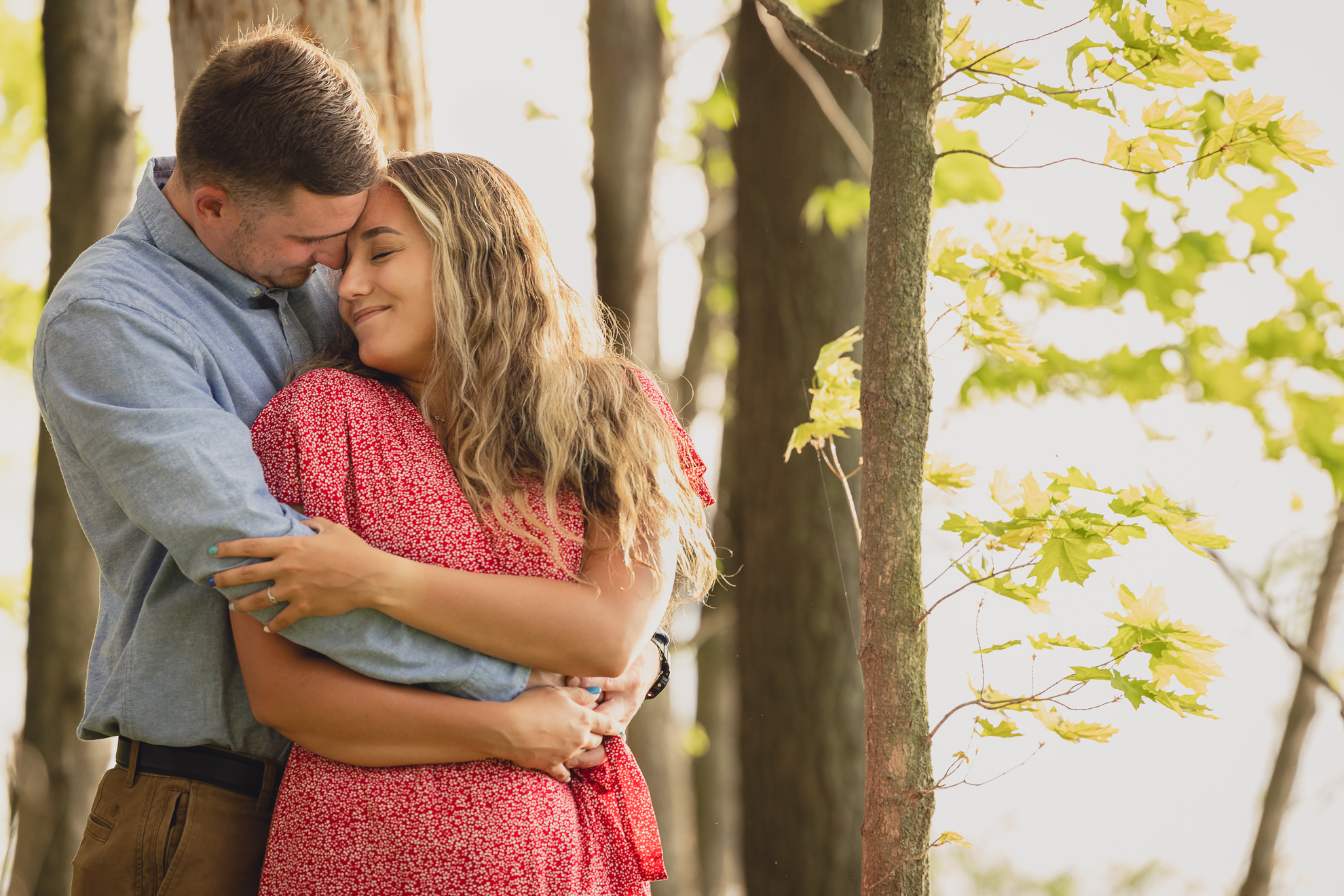 couple snuggles during wedding engagement proposal photography in woods by Lake Ontario Beach in Niagara County