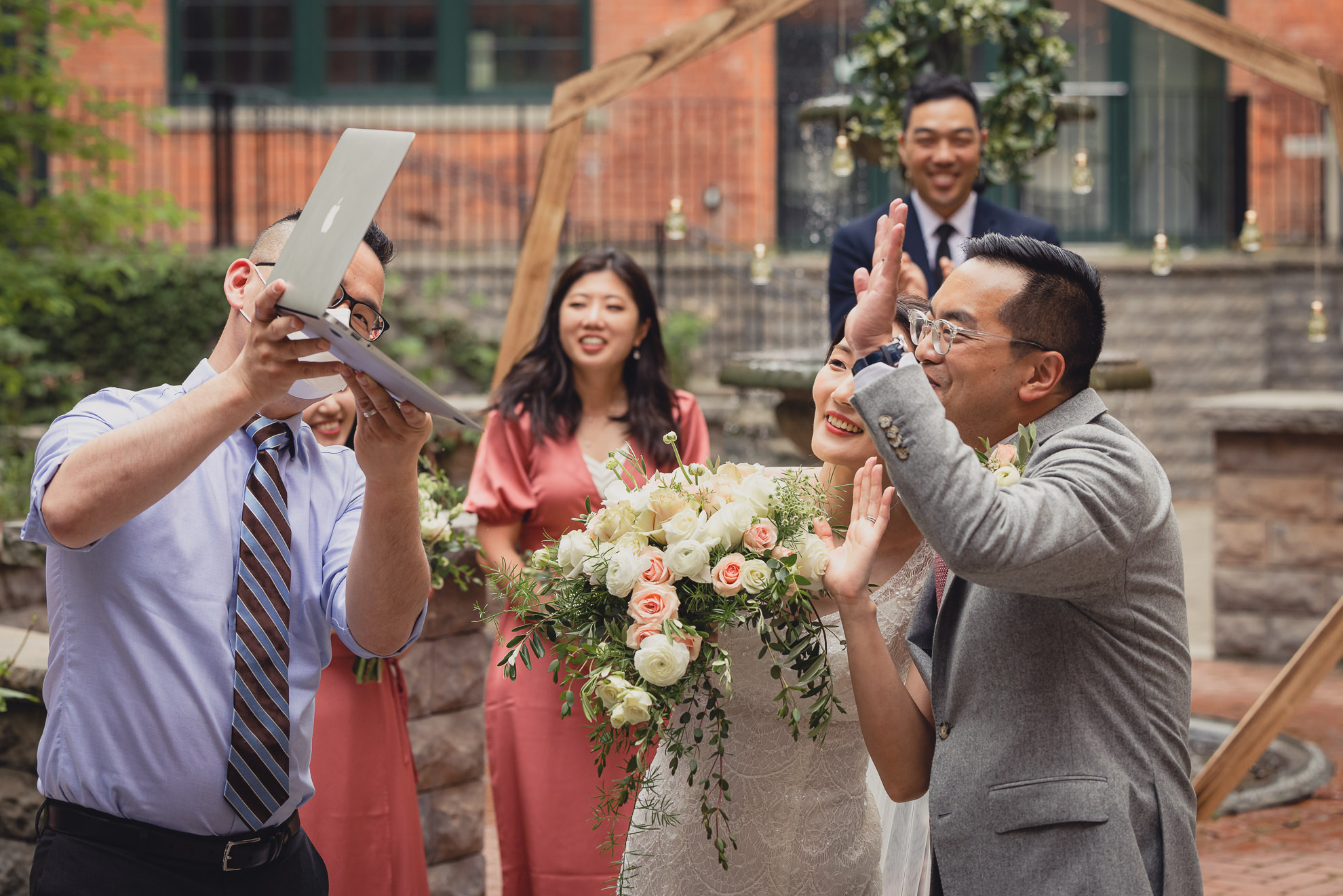 bride and groom wave to guests on zoom during wedding ceremony at the Foundry Suites in Buffalo, NY