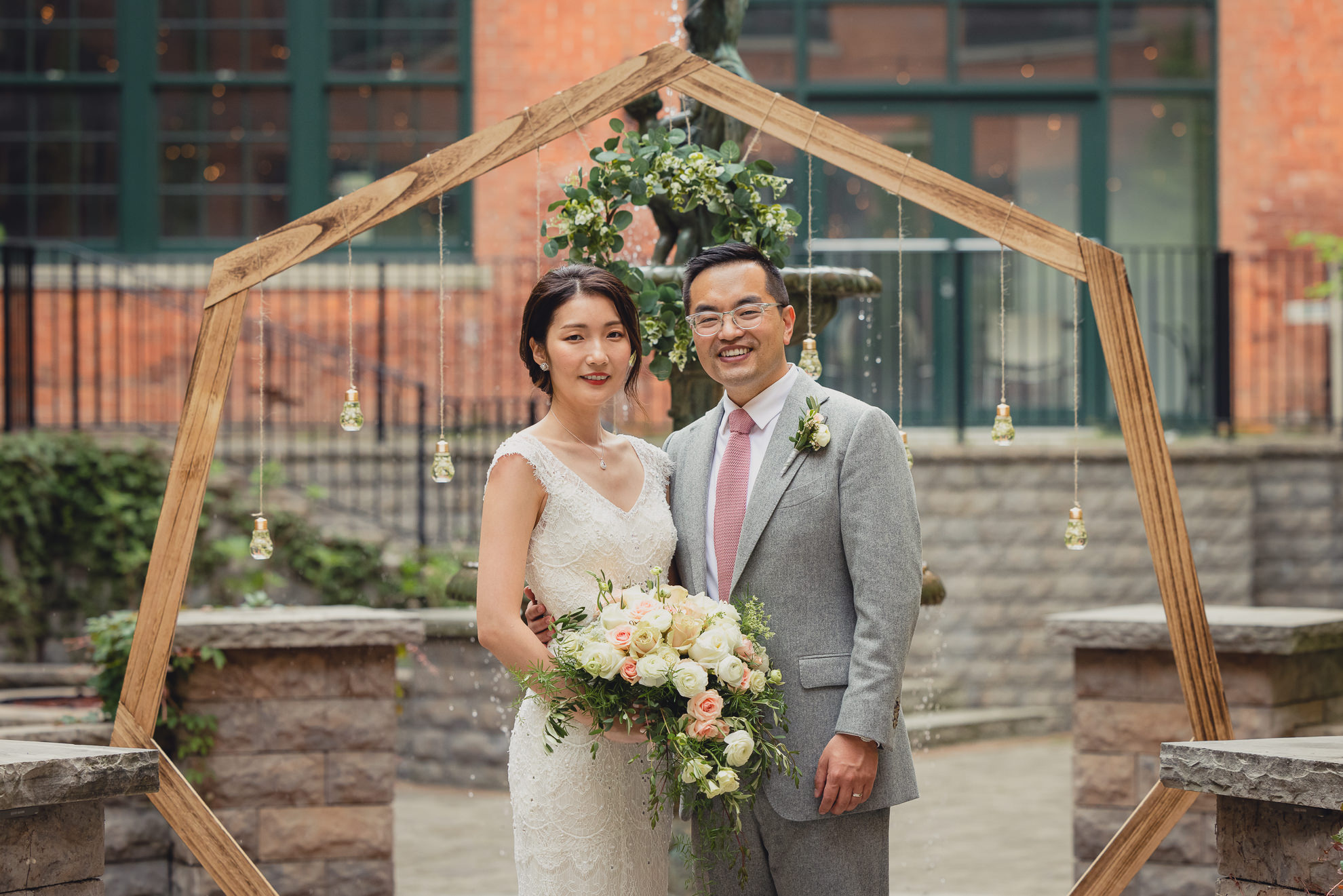 bride and groom pose for photographer during wedding at the Foundry Suites in Buffalo, NY