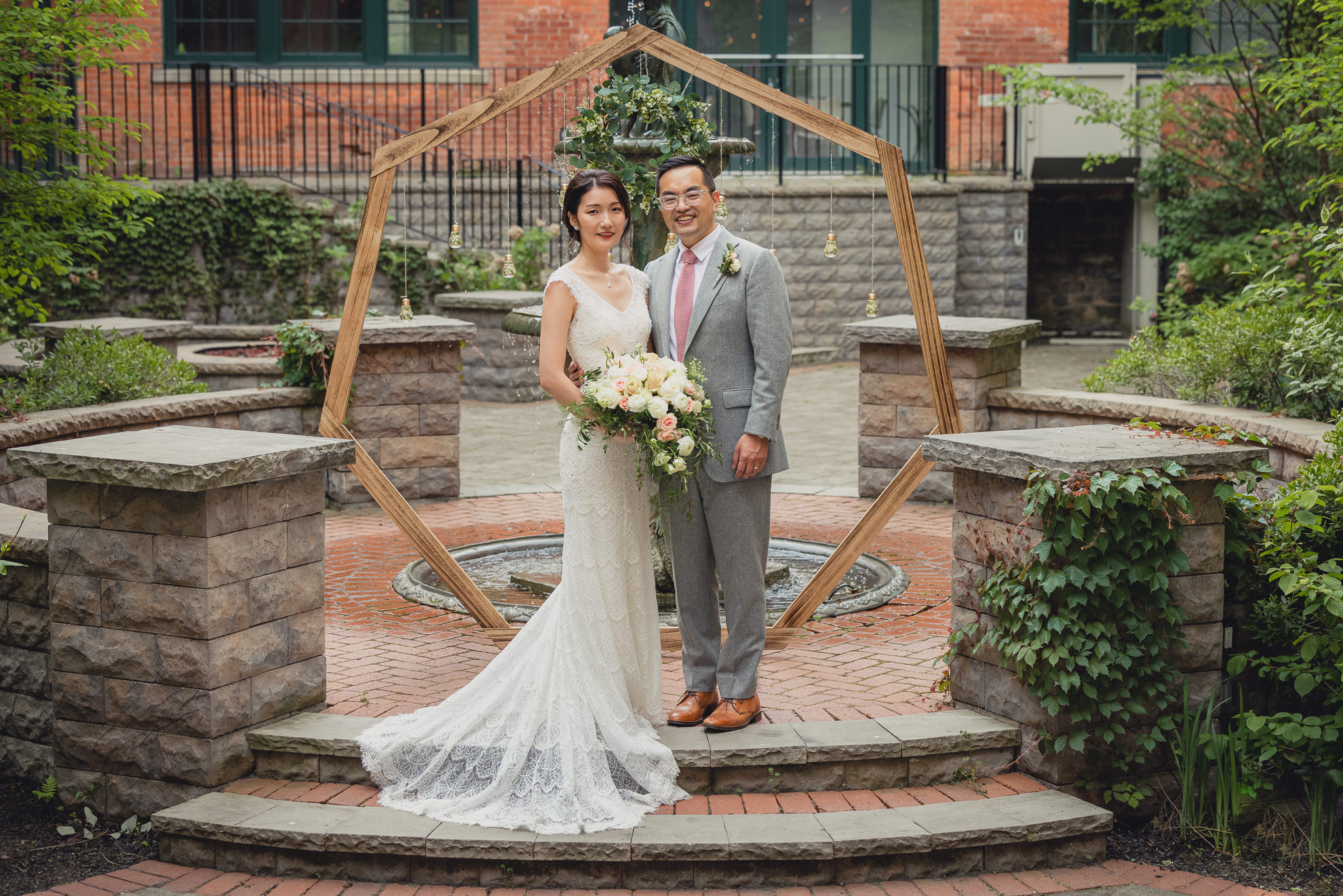 bride and groom pose for photographer during wedding at the Foundry Suites in Buffalo, NY
