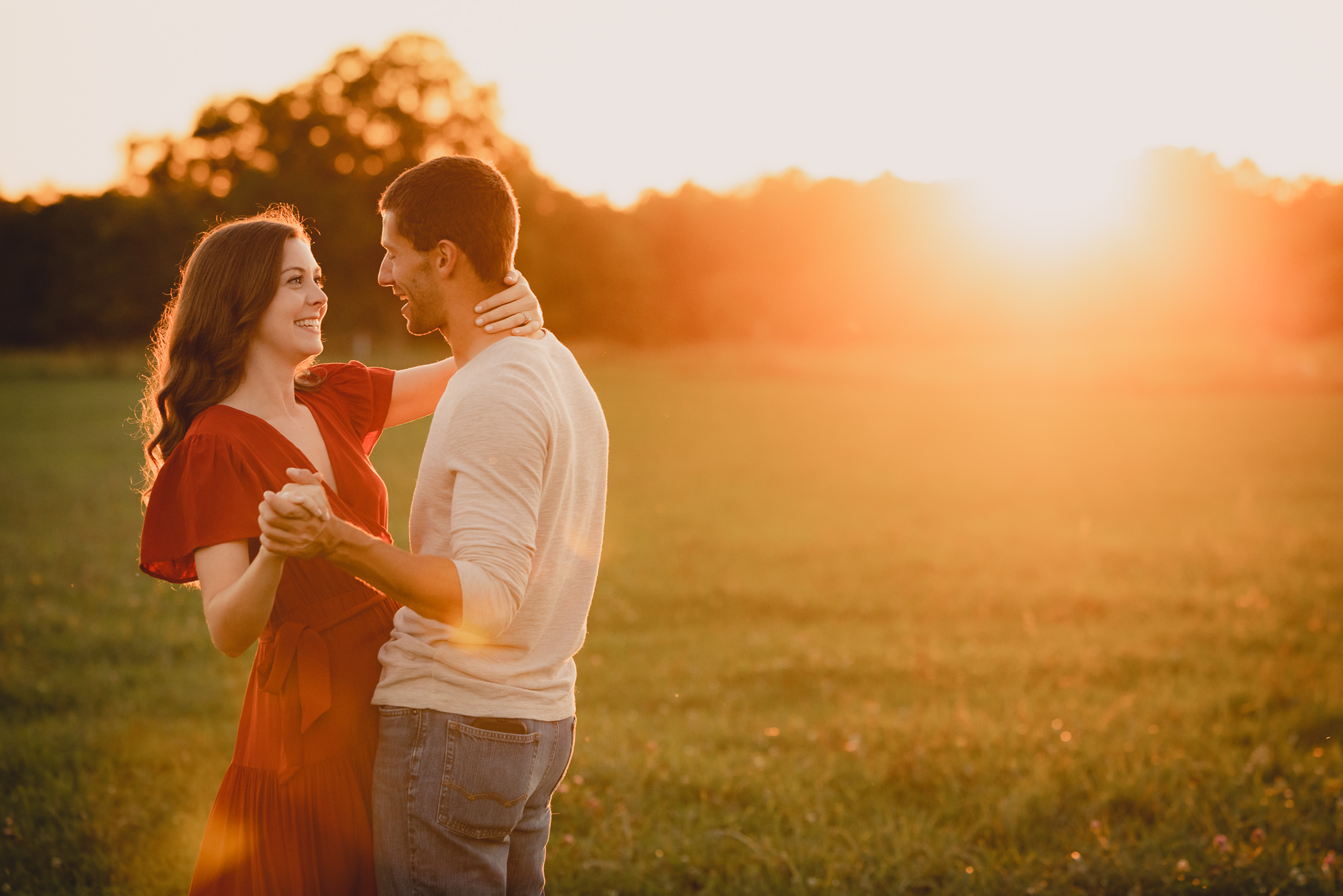 engaged couple poses in field during sunset at engagement photography session at best location near Buffalo, NY