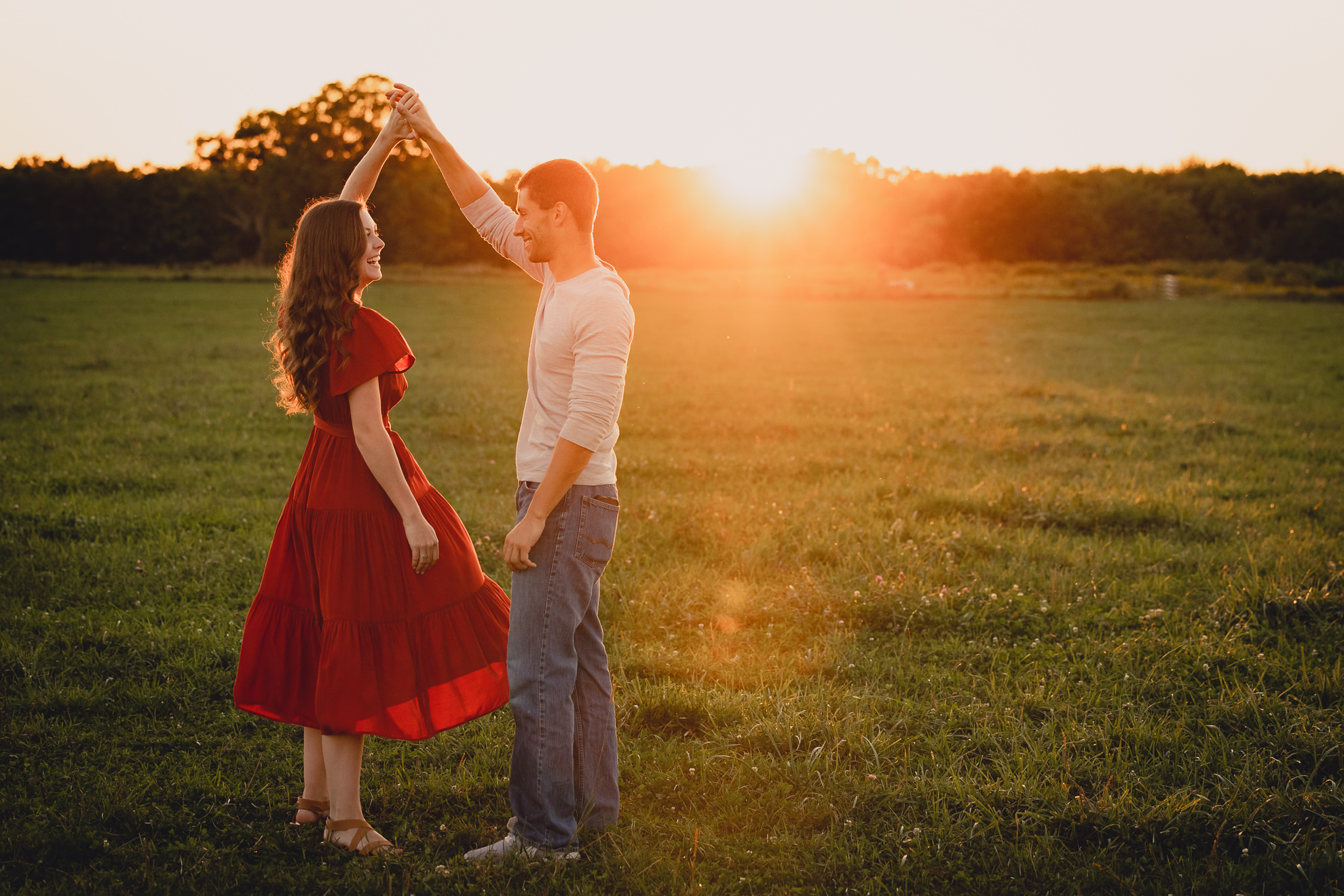 engaged couple poses in field during sunset at engagement photography session at best location near Buffalo, NY