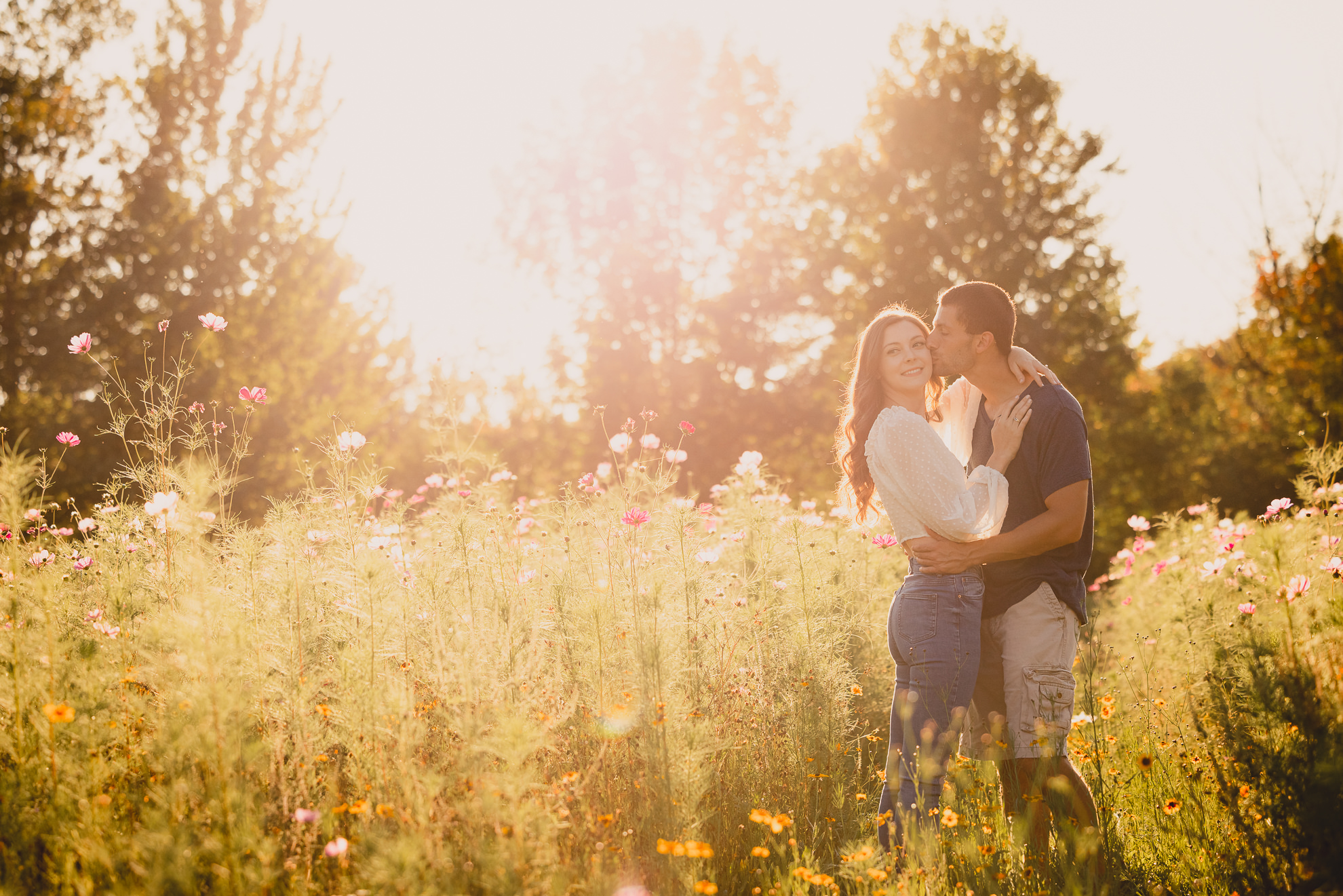 engaged couple poses in flower field during engagement photography session at best location near Buffalo, NY