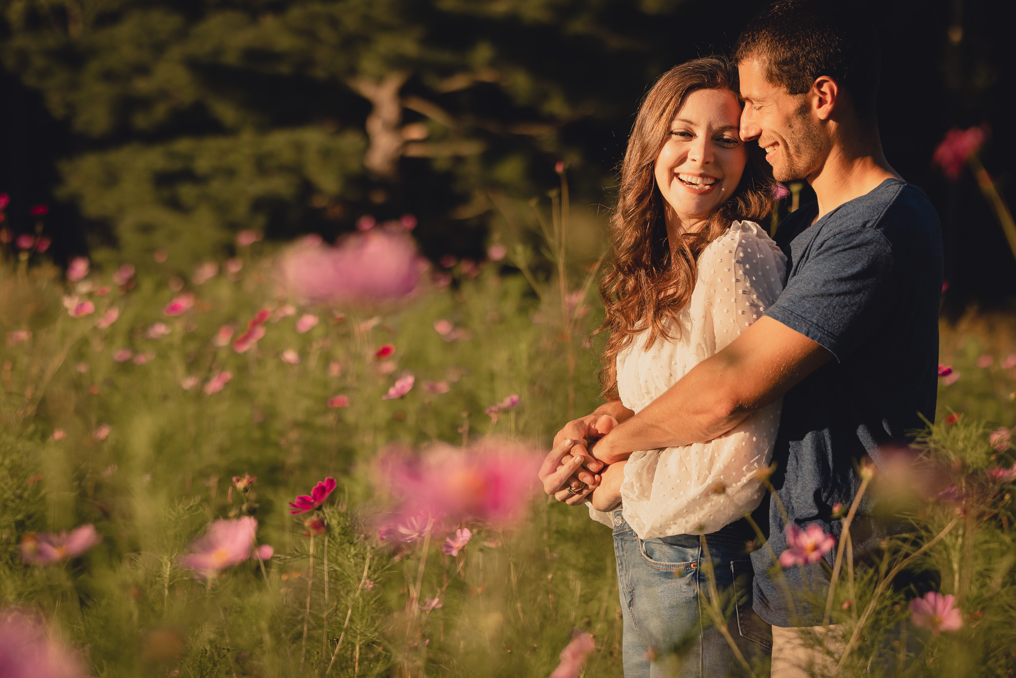 engaged couple laughs in flower field during engagement photography session at best location near Buffalo, NY