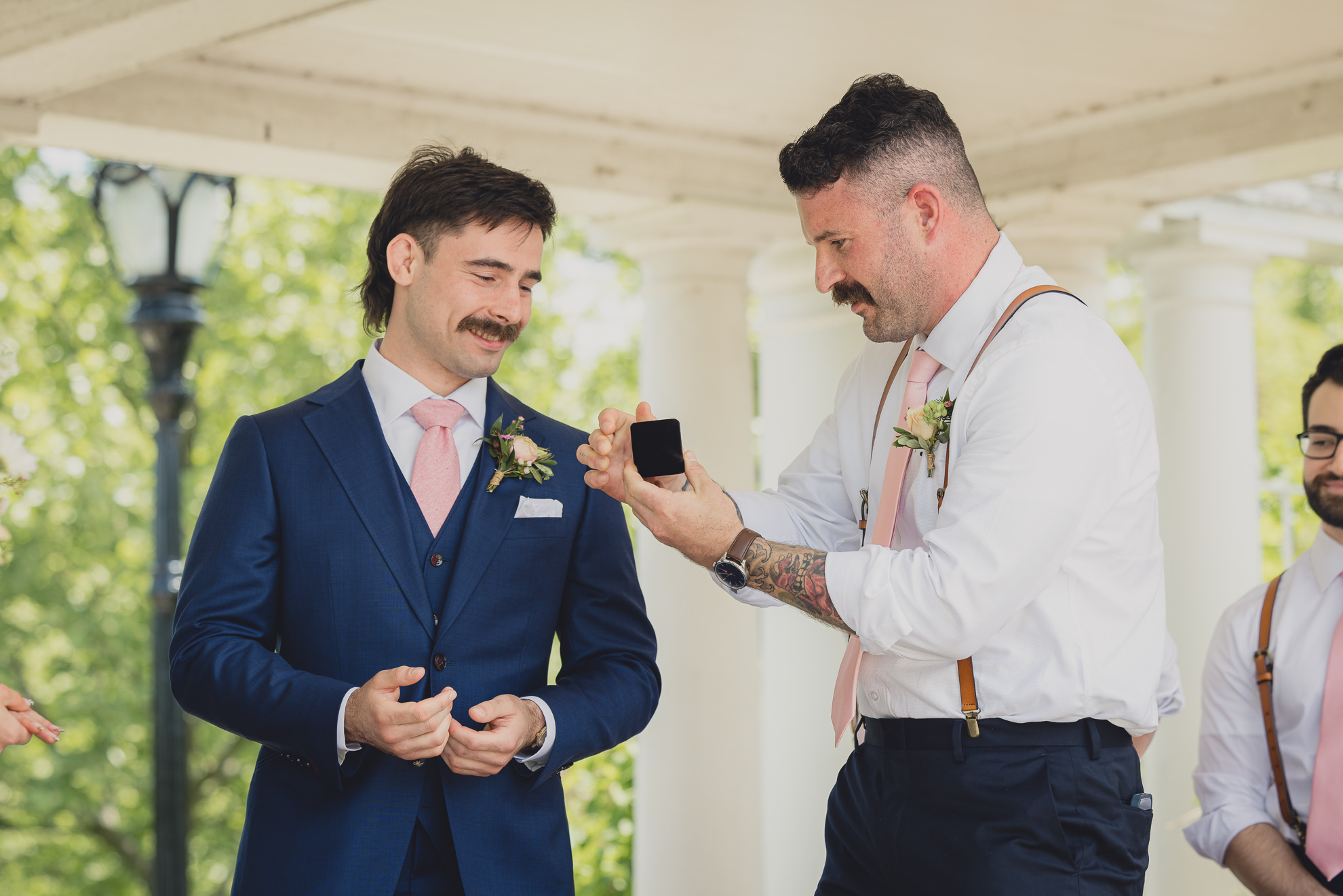 best man gives groom ring at the terrace at marcy casino rose garden wedding ceremony