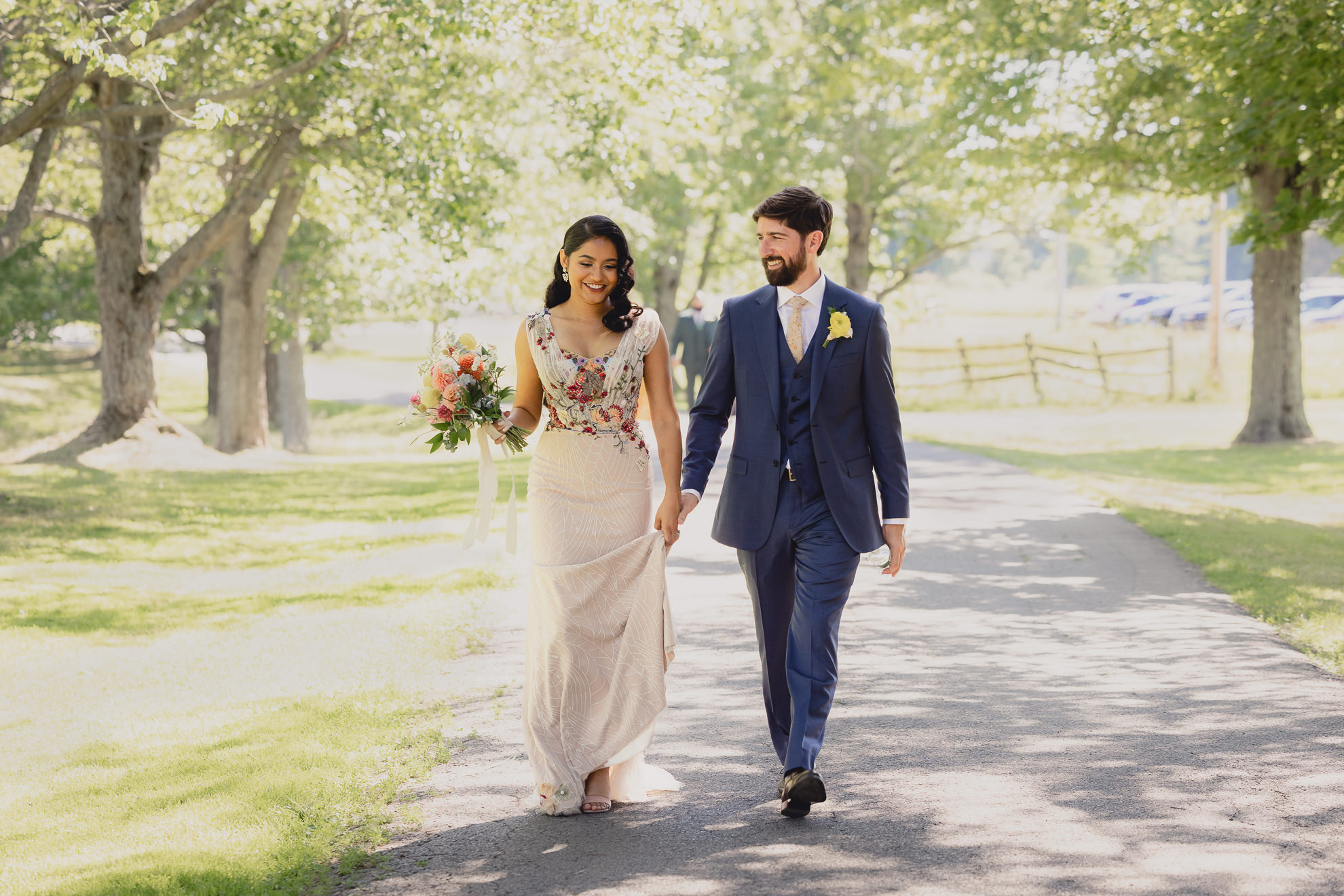 couple walks down road after wedding ceremony at mansion at Knox Farm in East Aurora, NY