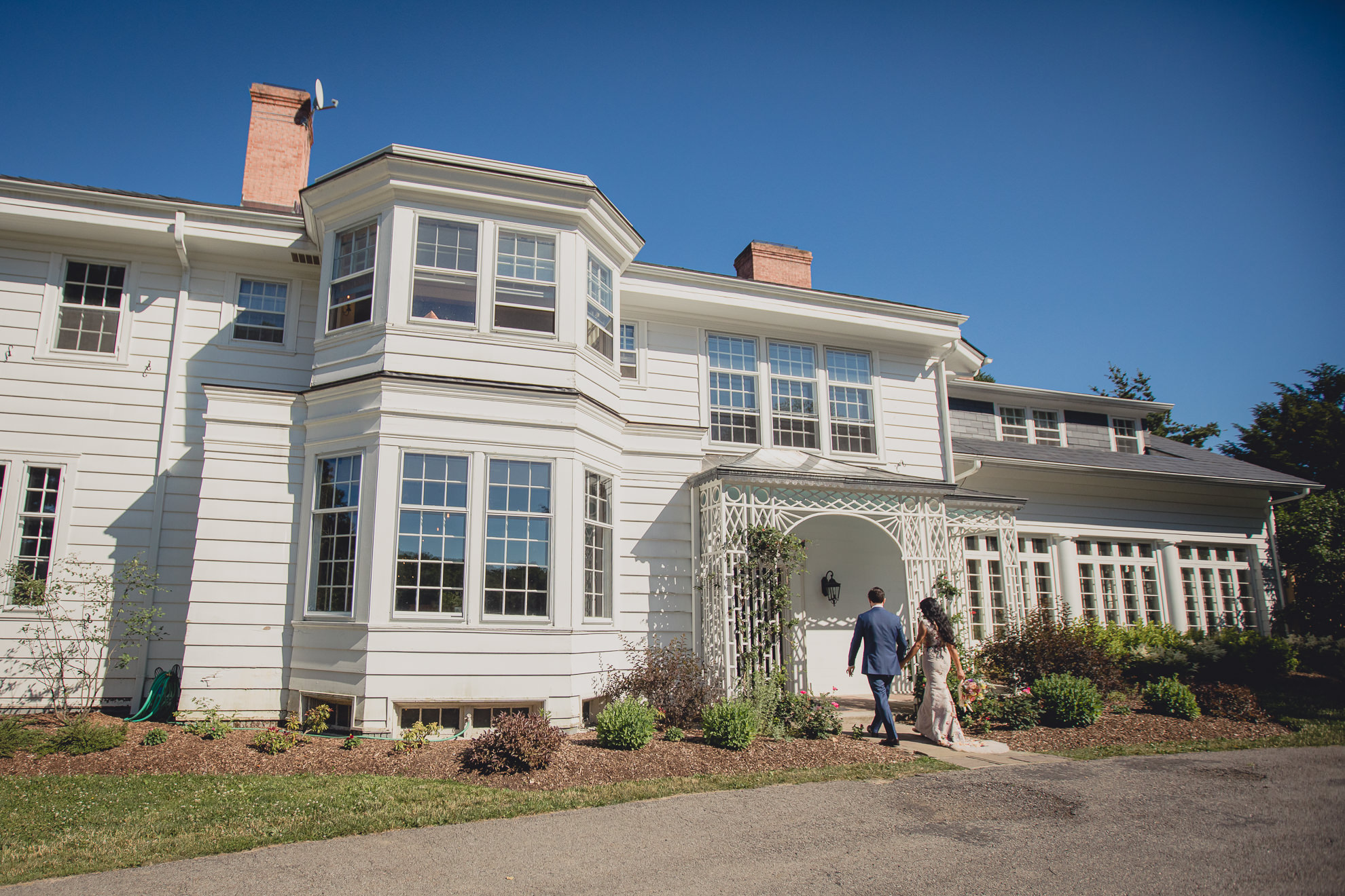 couple walks in to mansion at outdoor tented wedding reception at Knox Farm in East Aurora, NY