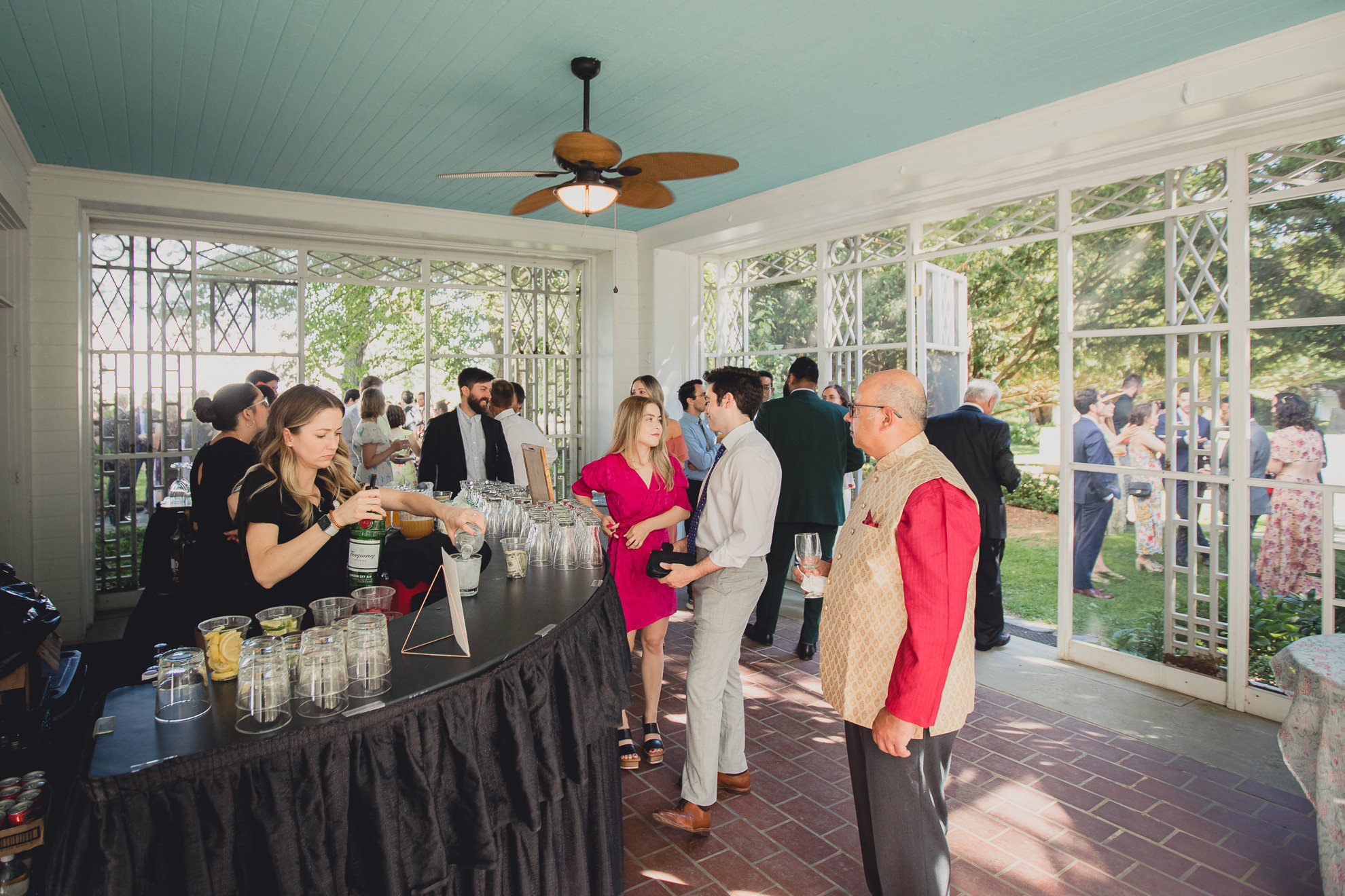 guests gather at bar for drinks during cocktail hour at outdoor tented wedding reception at Knox Farm in East Aurora, NY