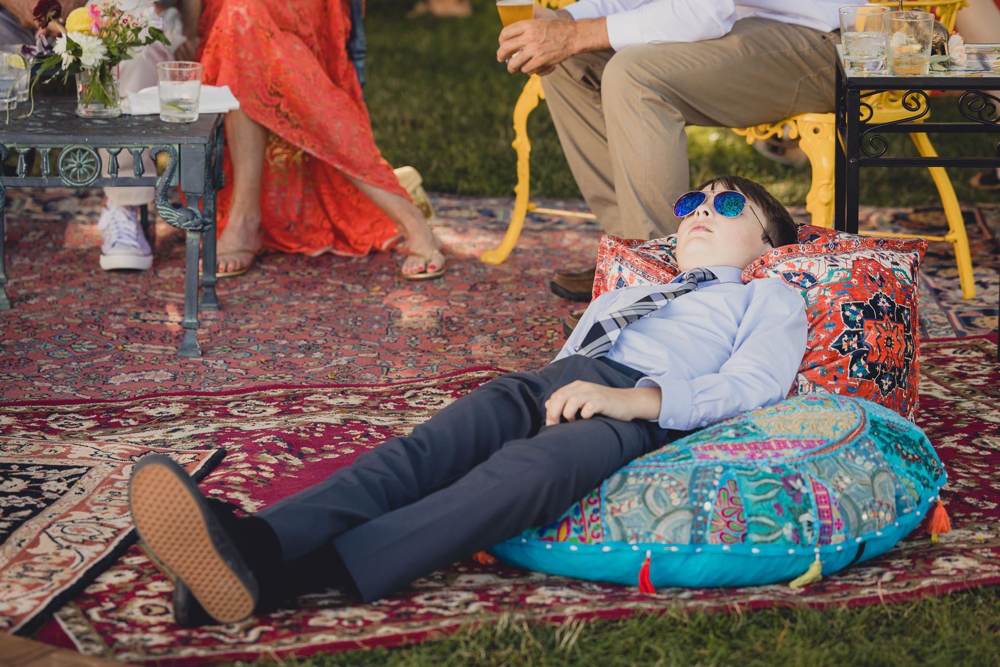 boy naps at outdoor tented wedding reception at Knox Farm in East Aurora, NY