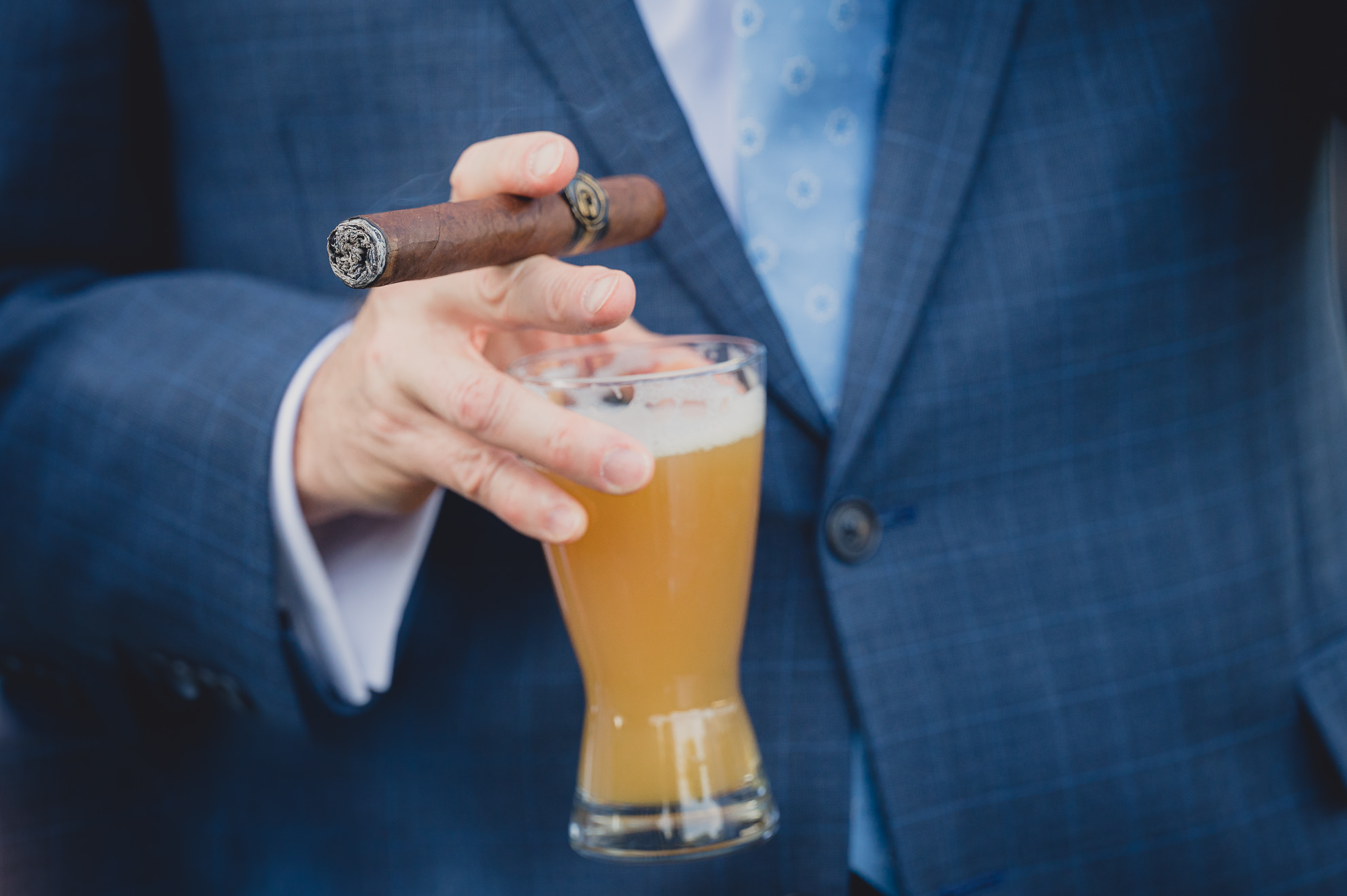 groom smokes cigar at outdoor tented wedding reception at Knox Farm in East Aurora, NY