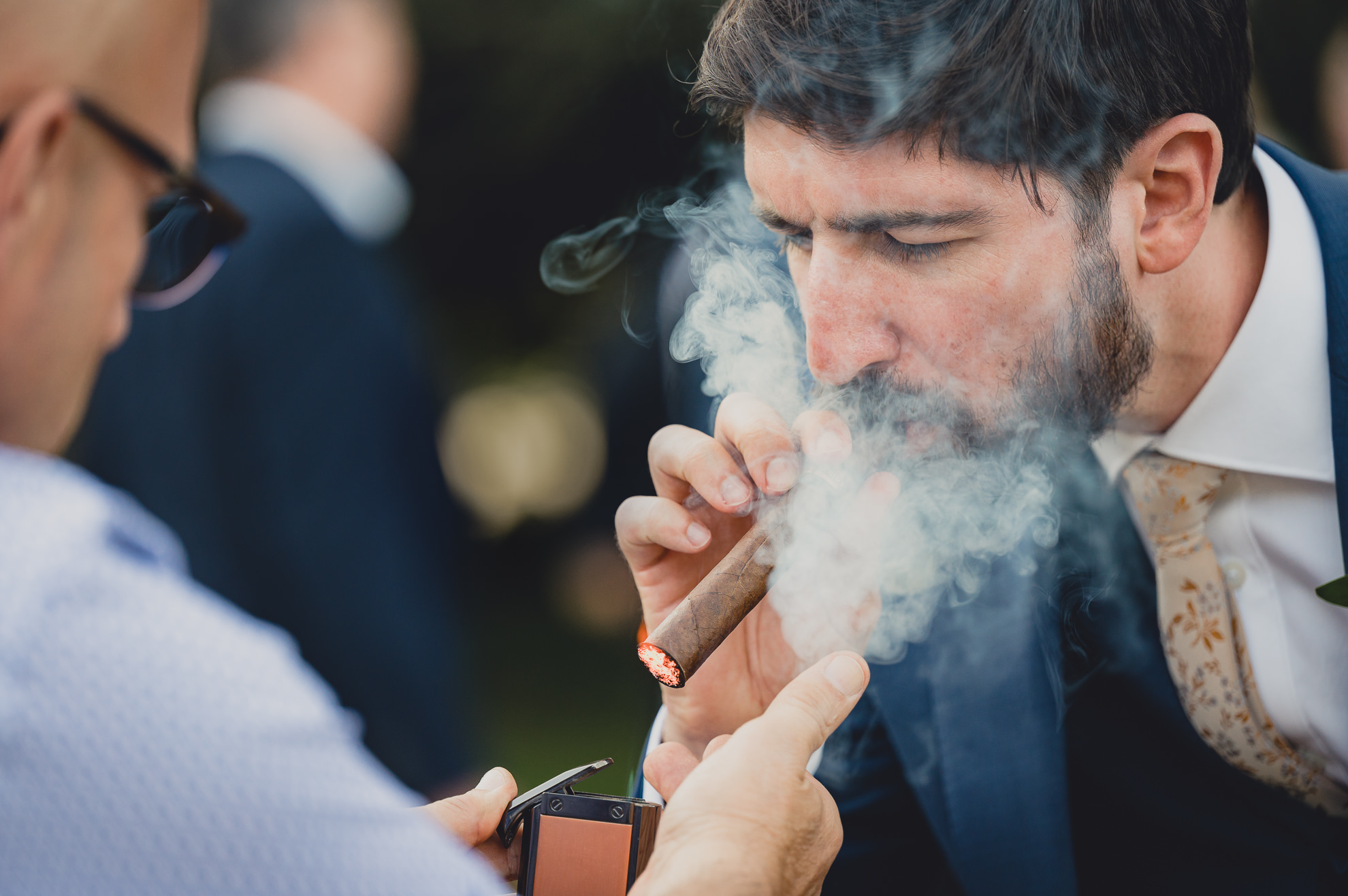 groom smokes cigar at outdoor tented wedding reception at Knox Farm in East Aurora, NY