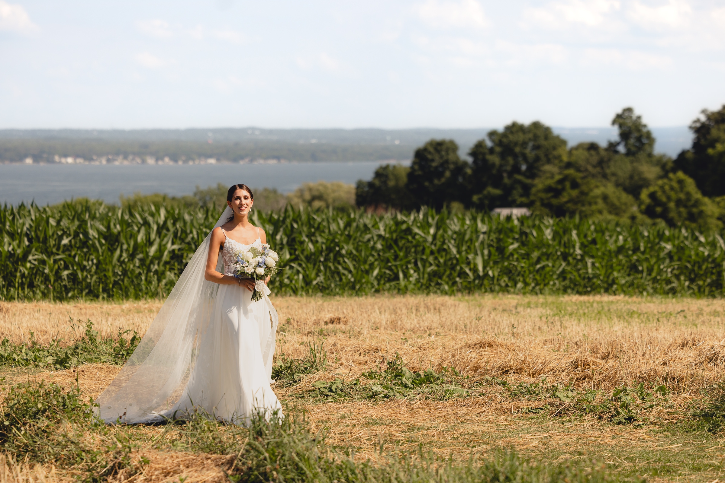 bride walks through corn field at wedding ceremony at The North Farm overlooking Seneca Lake in Geneva, NY