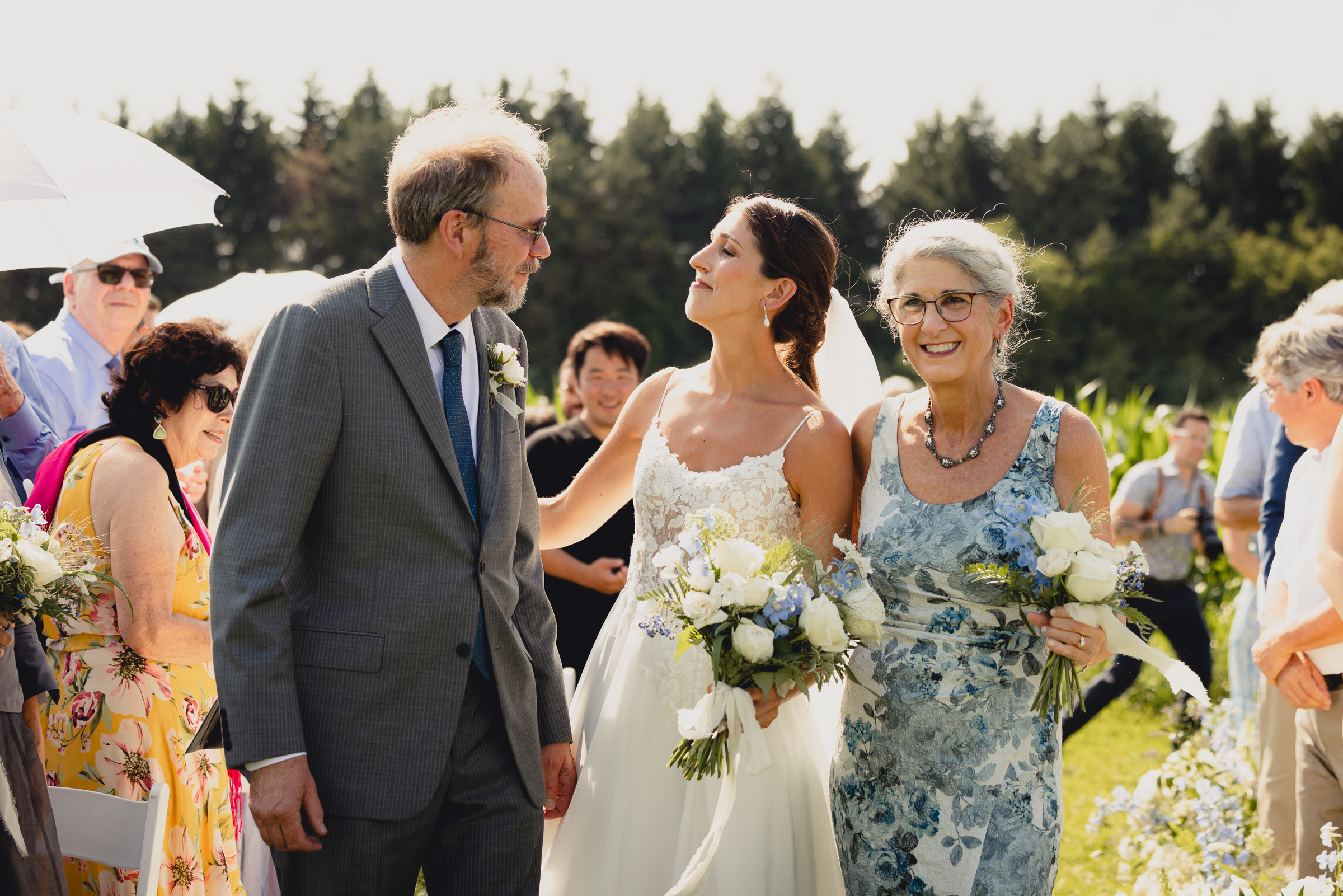 bride walks down aisle with parents at wedding ceremony at The North Farm overlooking Seneca Lake in Geneva, NY