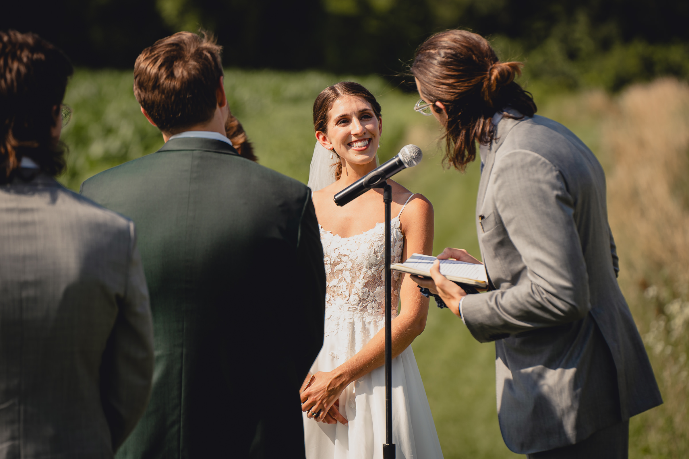 bride smiles at officiant at wedding ceremony at The North Farm overlooking Seneca Lake in Geneva, NY