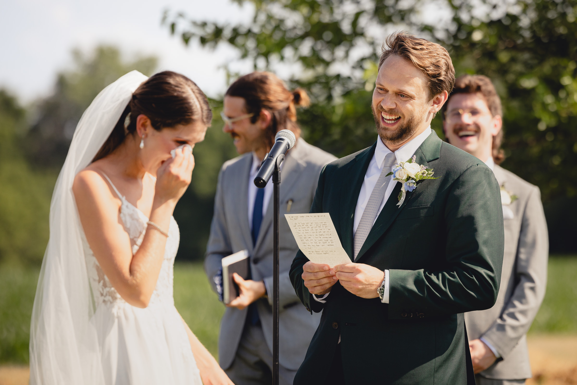 groom says vows while bride wipes tear at wedding ceremony at The North Farm overlooking Seneca Lake in Geneva, NY