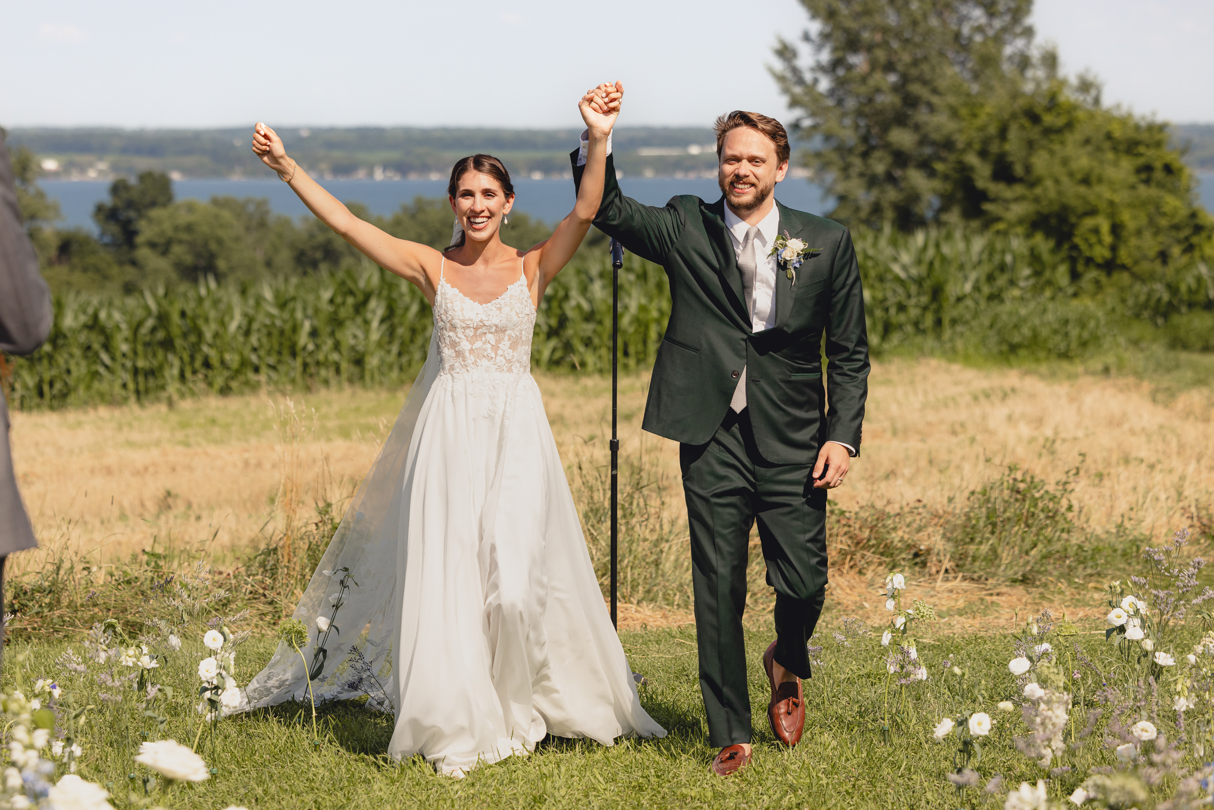 bride and groom raise arms to cheer at wedding ceremony at The North Farm overlooking Seneca Lake in Geneva, NY