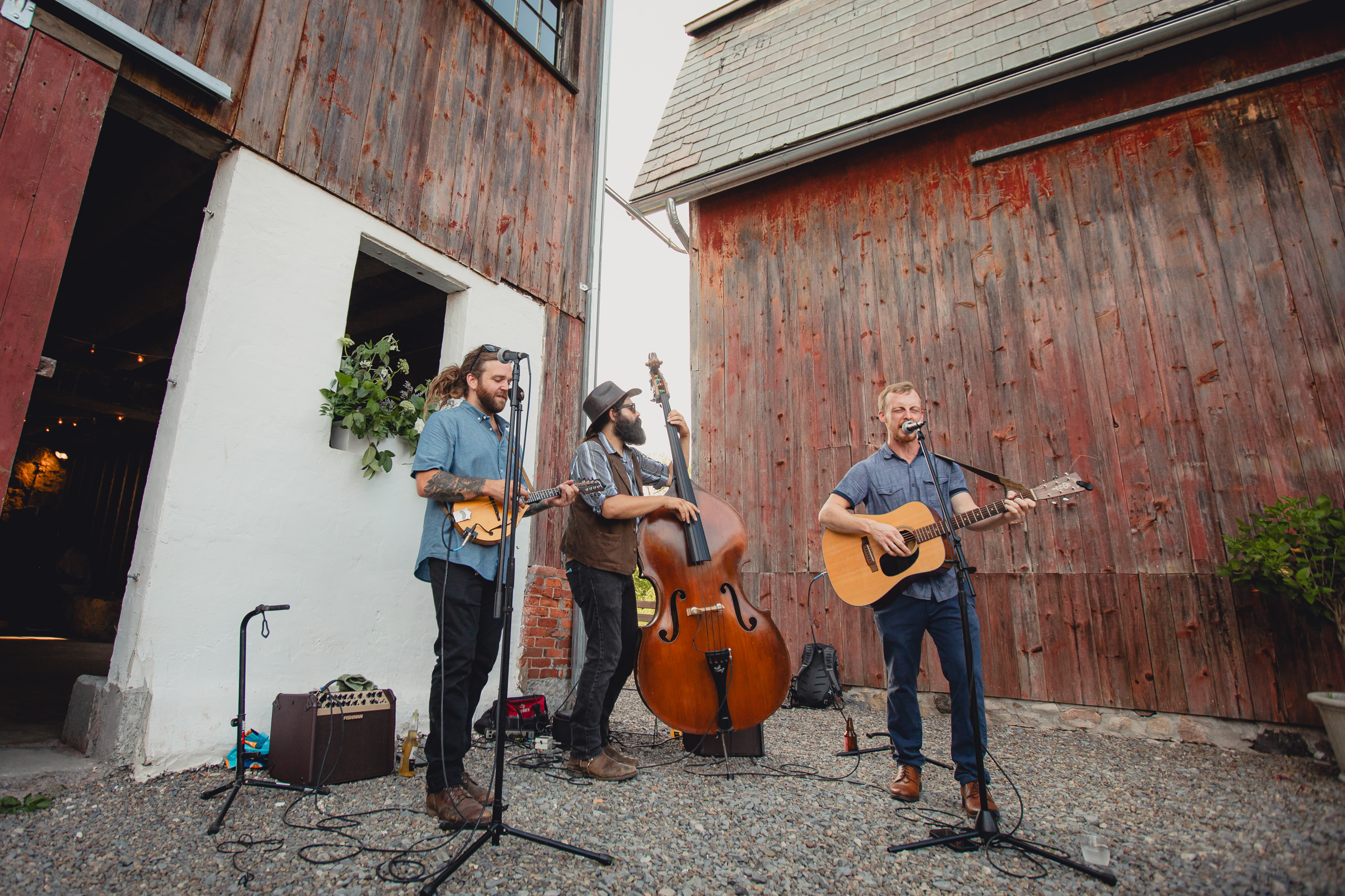 Musicians play in front of The North Farm barns at a wedding reception in Geneva, NY in the Finger Lakes region