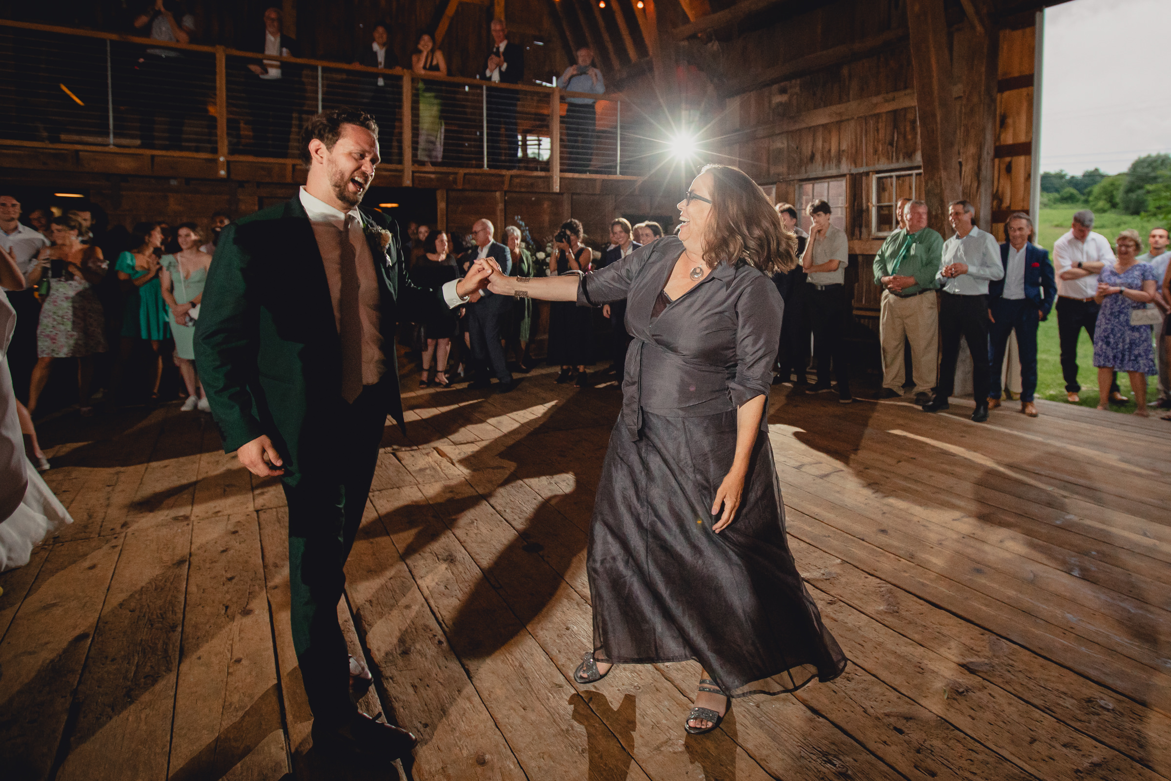 mother and groom dance at wedding reception in barn at The North Farm in Geneva, NY