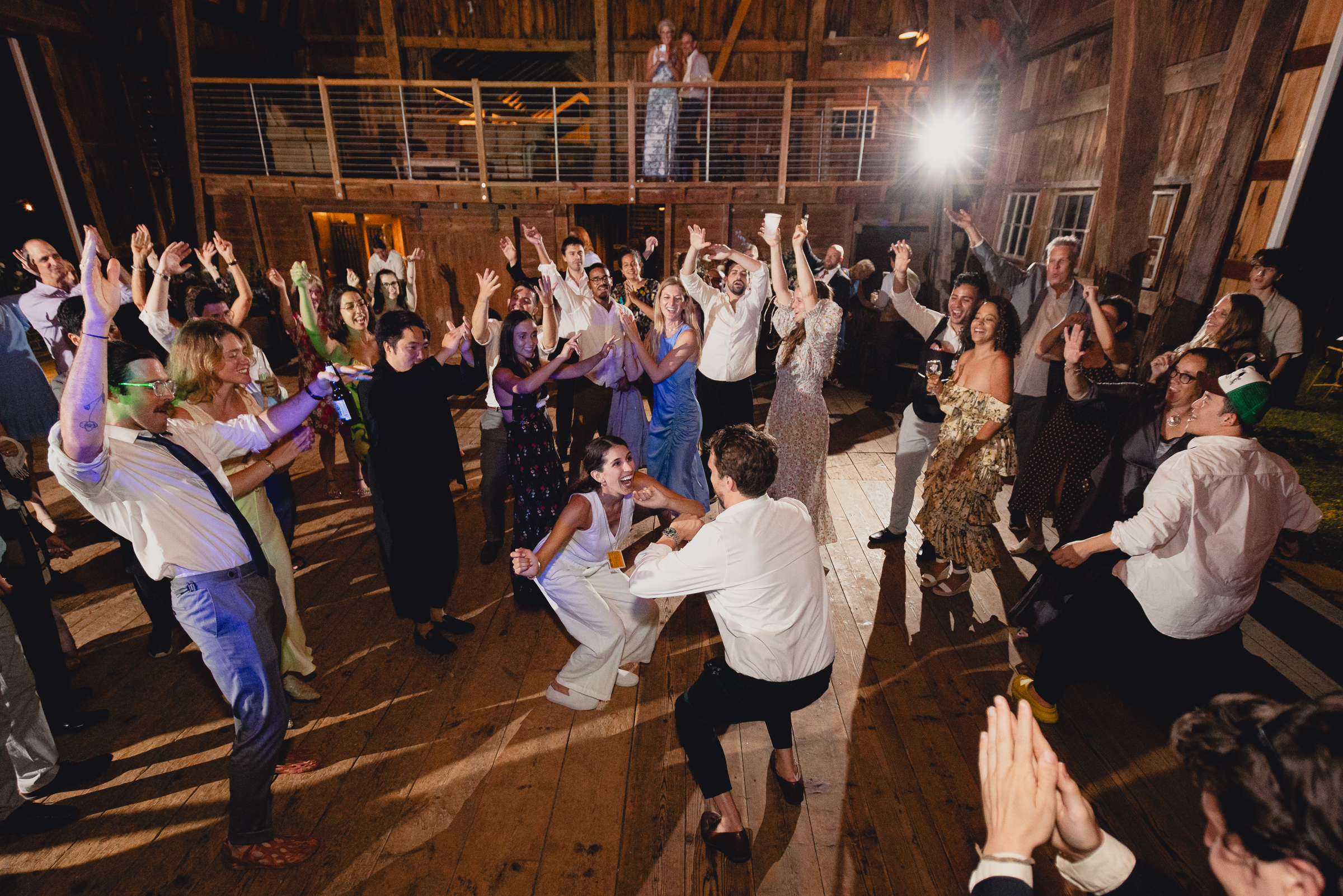bride and groom dance with guests at wedding reception in barn at The North Farm in Geneva, NY