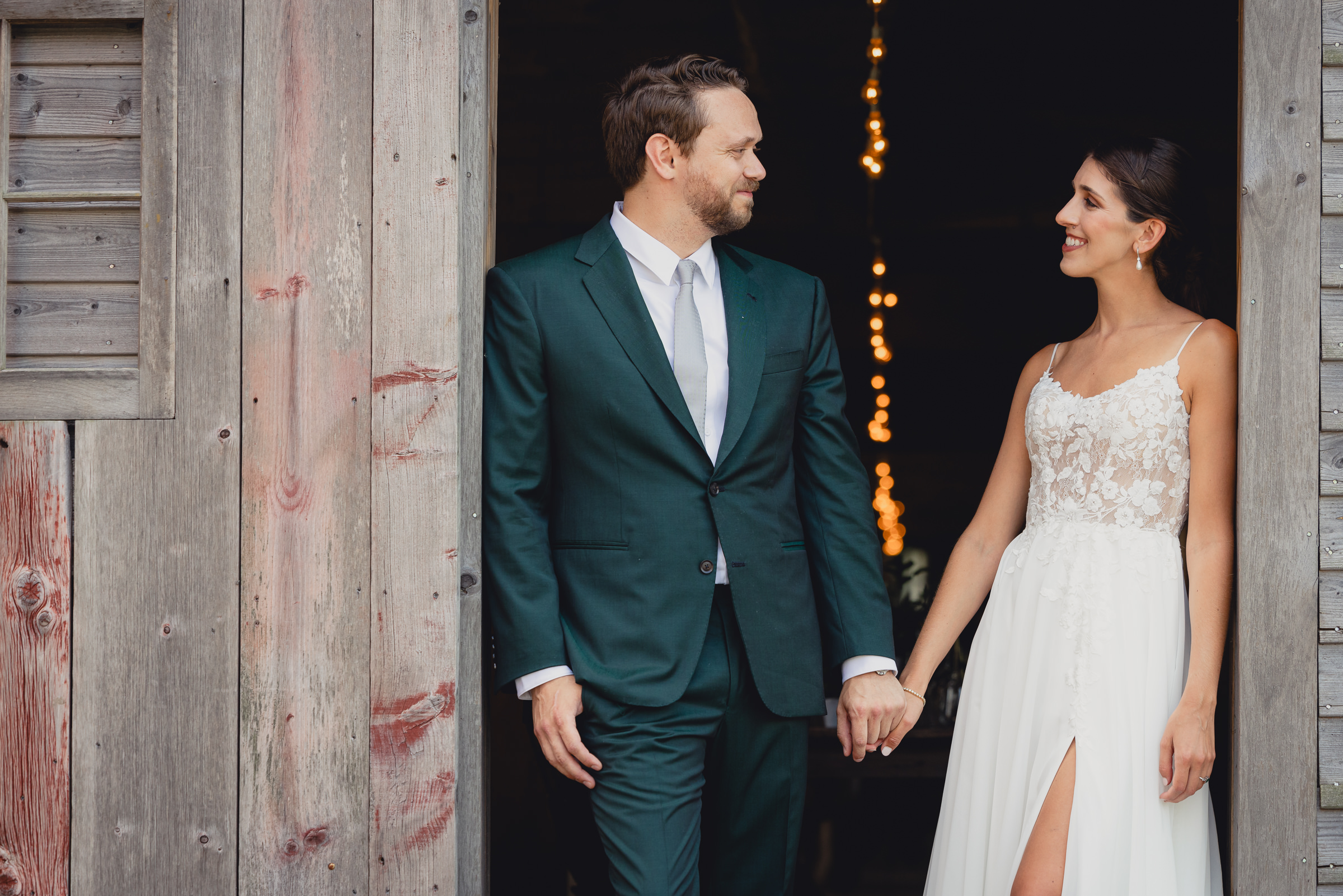 Bride and groom pose for portraits in front of The North Farm barns at a wedding in Geneva, NY