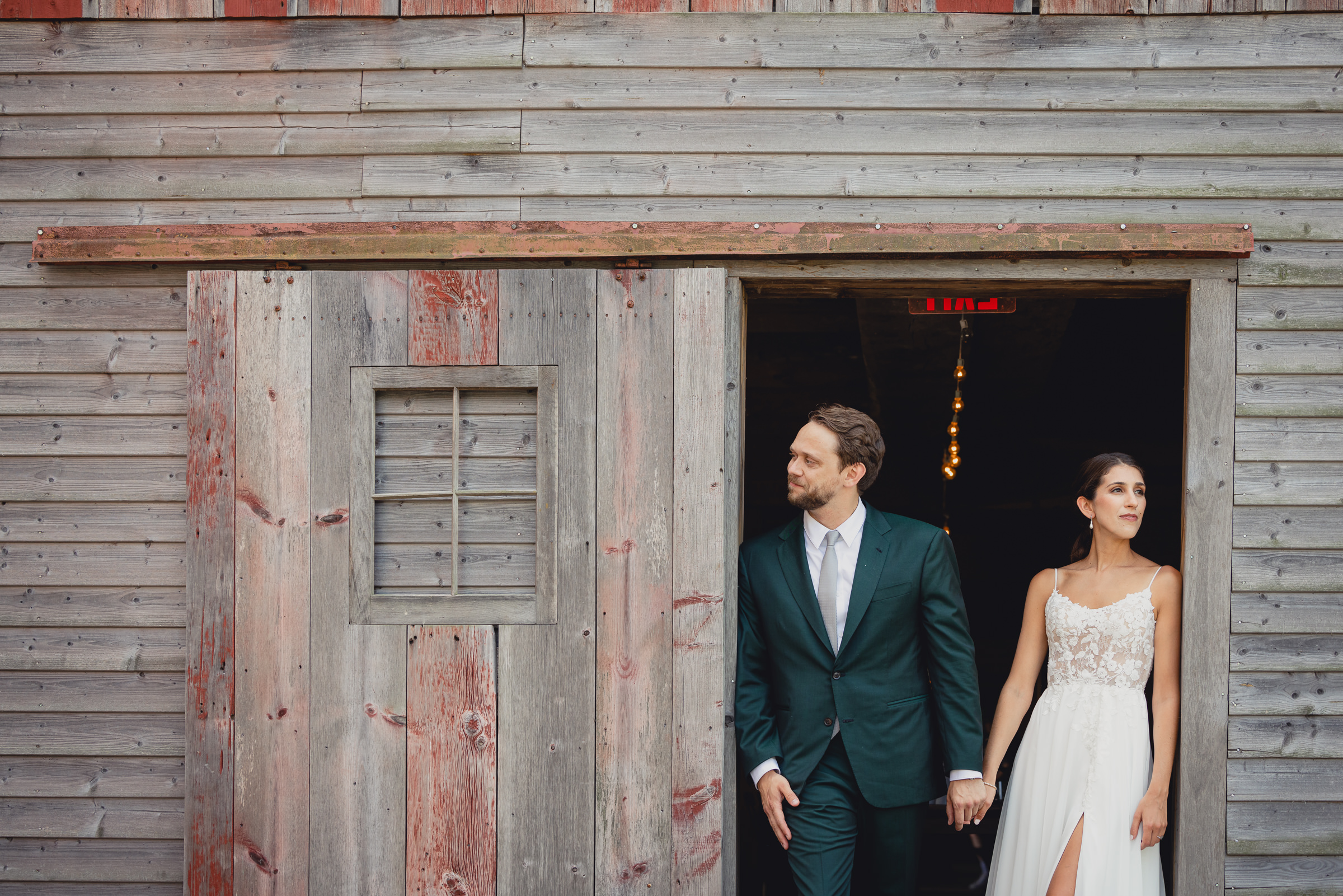 Bride and groom pose for portraits in front of The North Farm barns at a wedding in Geneva, NY