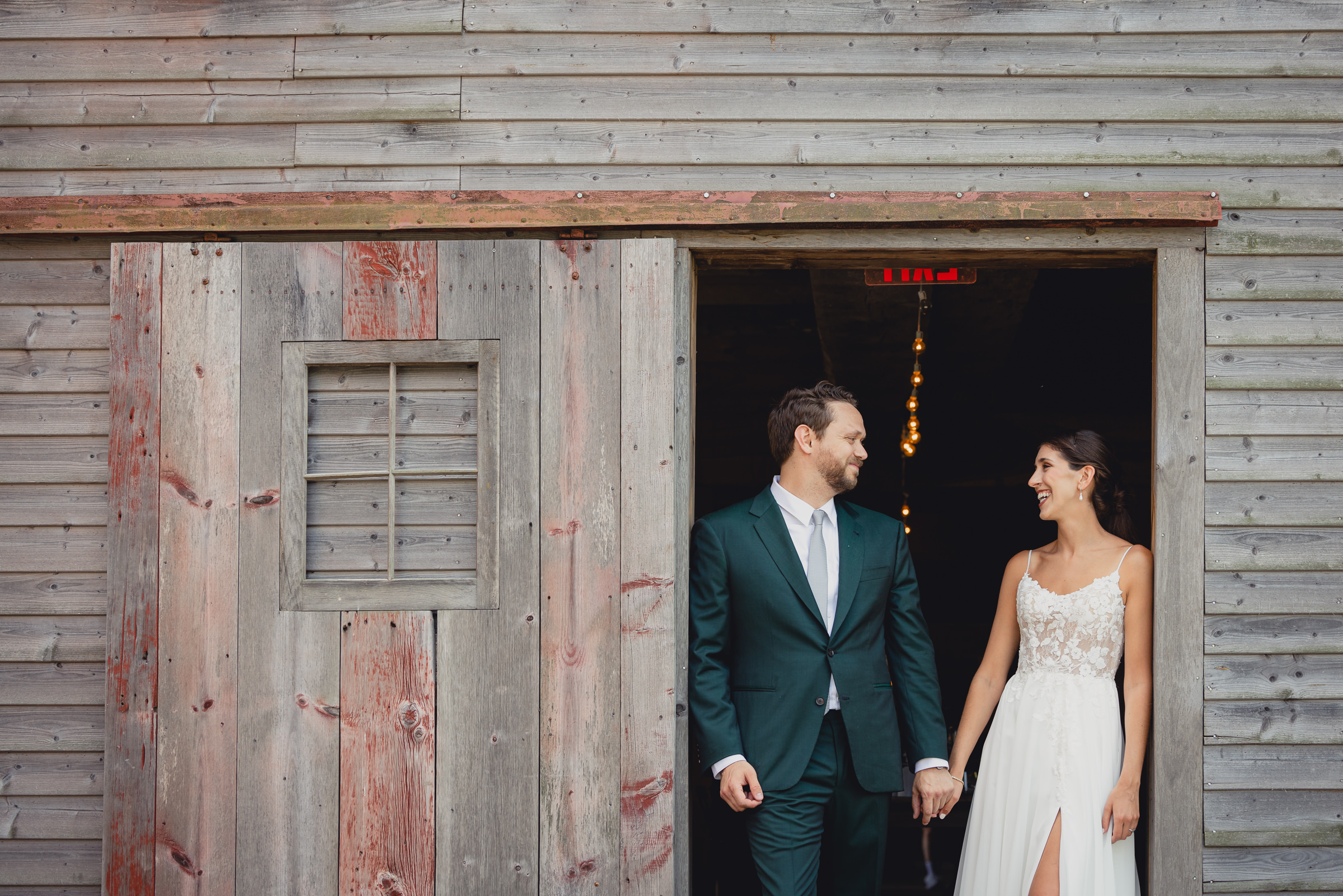 Bride and groom pose for portraits in front of The North Farm barns at a wedding in Geneva, NY