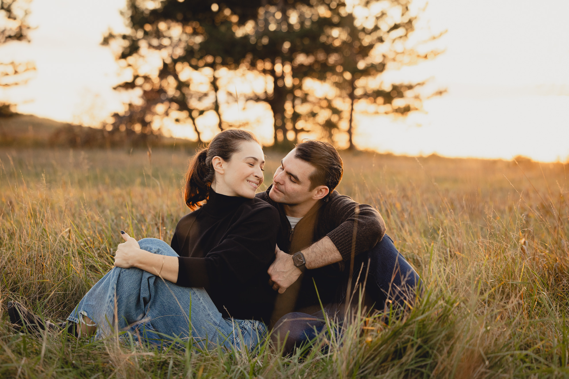 couples sits in field at Tifft Natre Preserve at sunset during wedding engagement photos in Buffalo NY