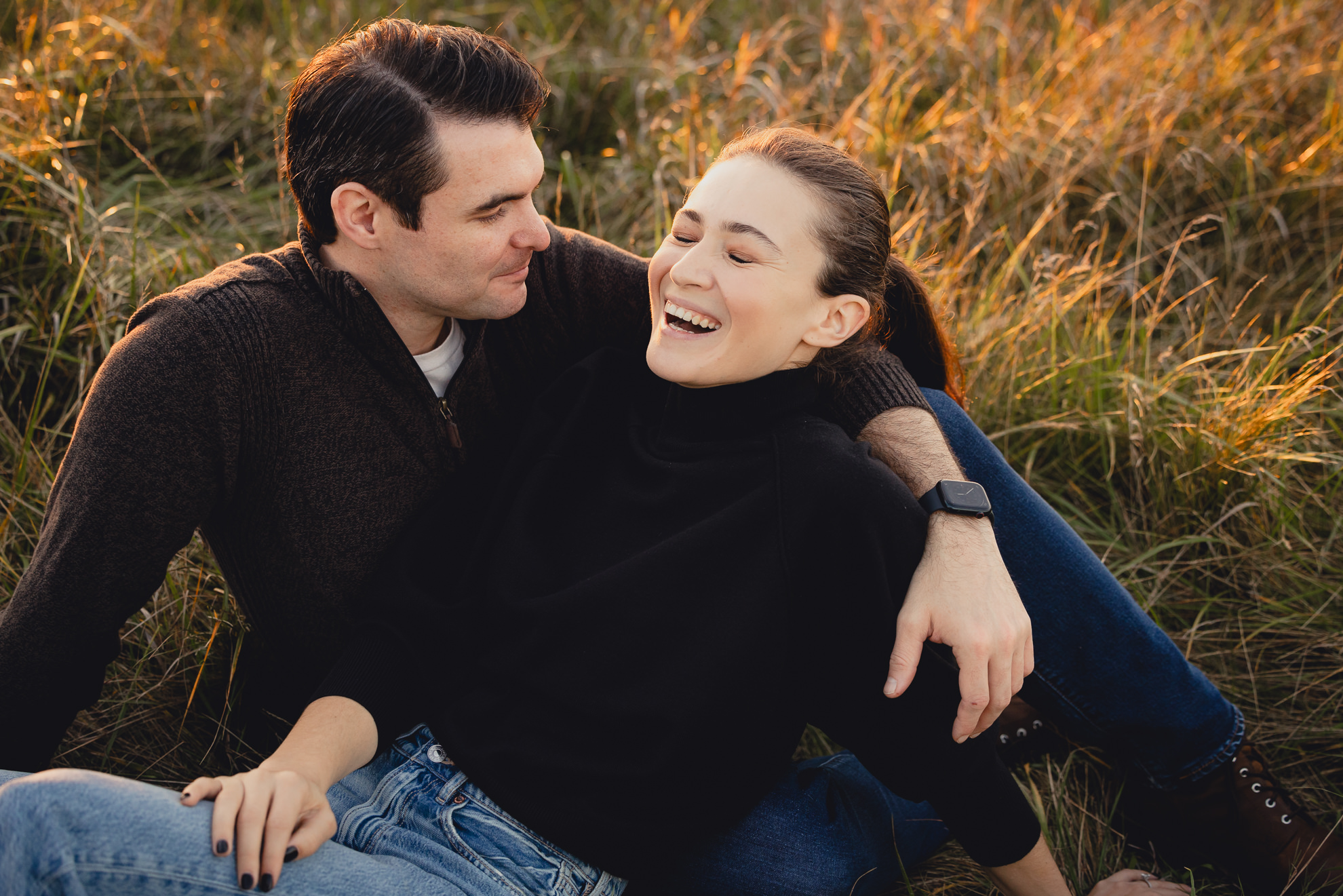 couple laughs in field at Tifft Natre Preserve at sunset during wedding engagement photos in Buffalo NY