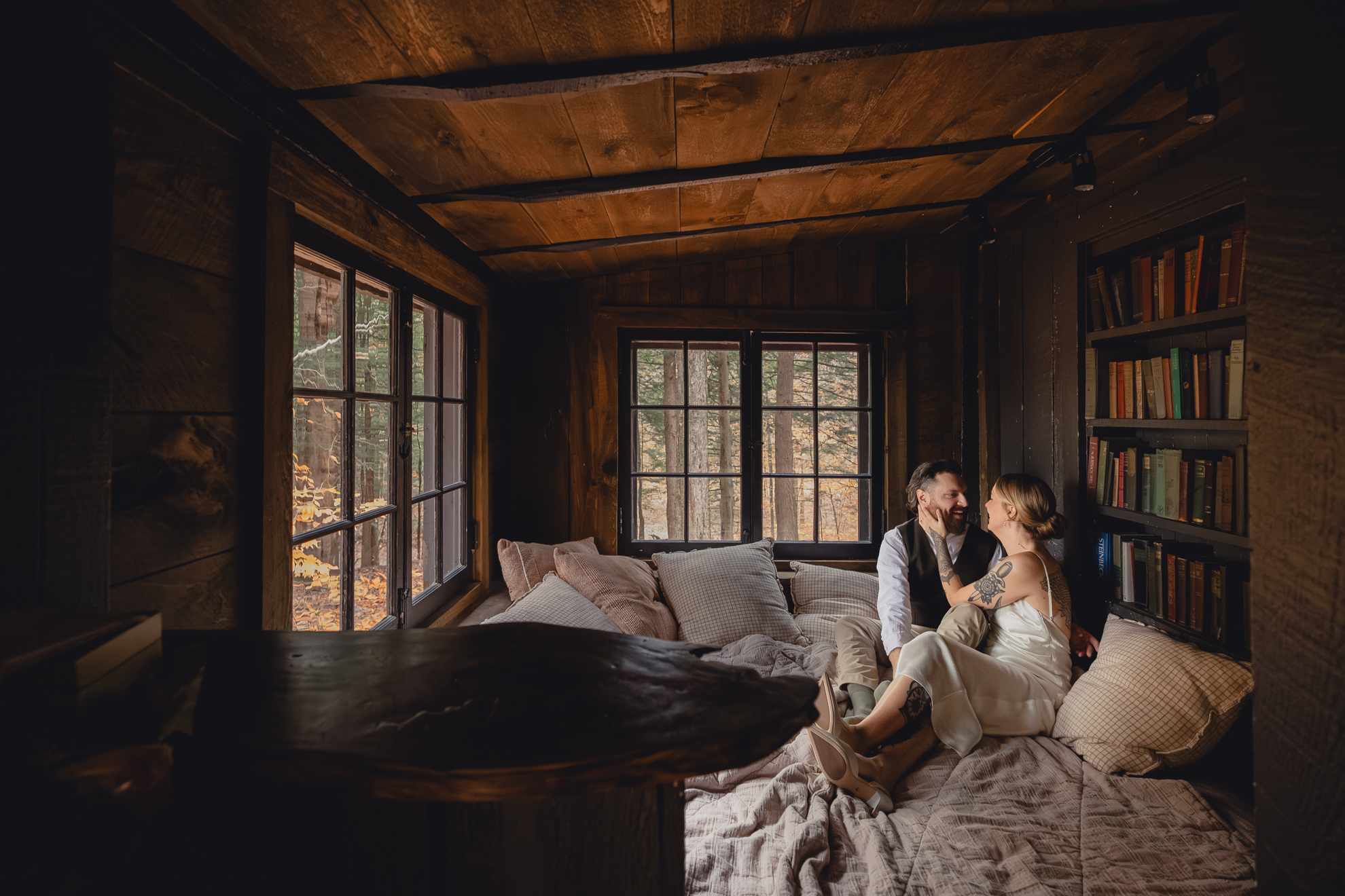 bride and groom snuggle in reading nook in Langston Cottage at Vanderkamp NY before fall wedding elopement in Adirondacks