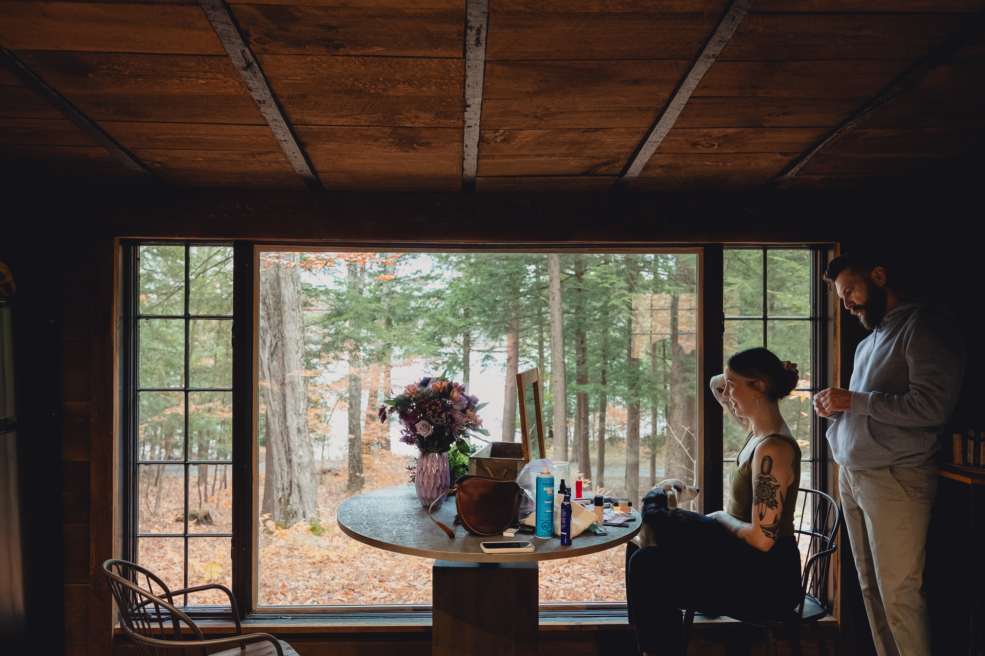 groom helps bride with hair at Langston Cottage at Vanderkamp NY before wedding elopement in the Adirondacks