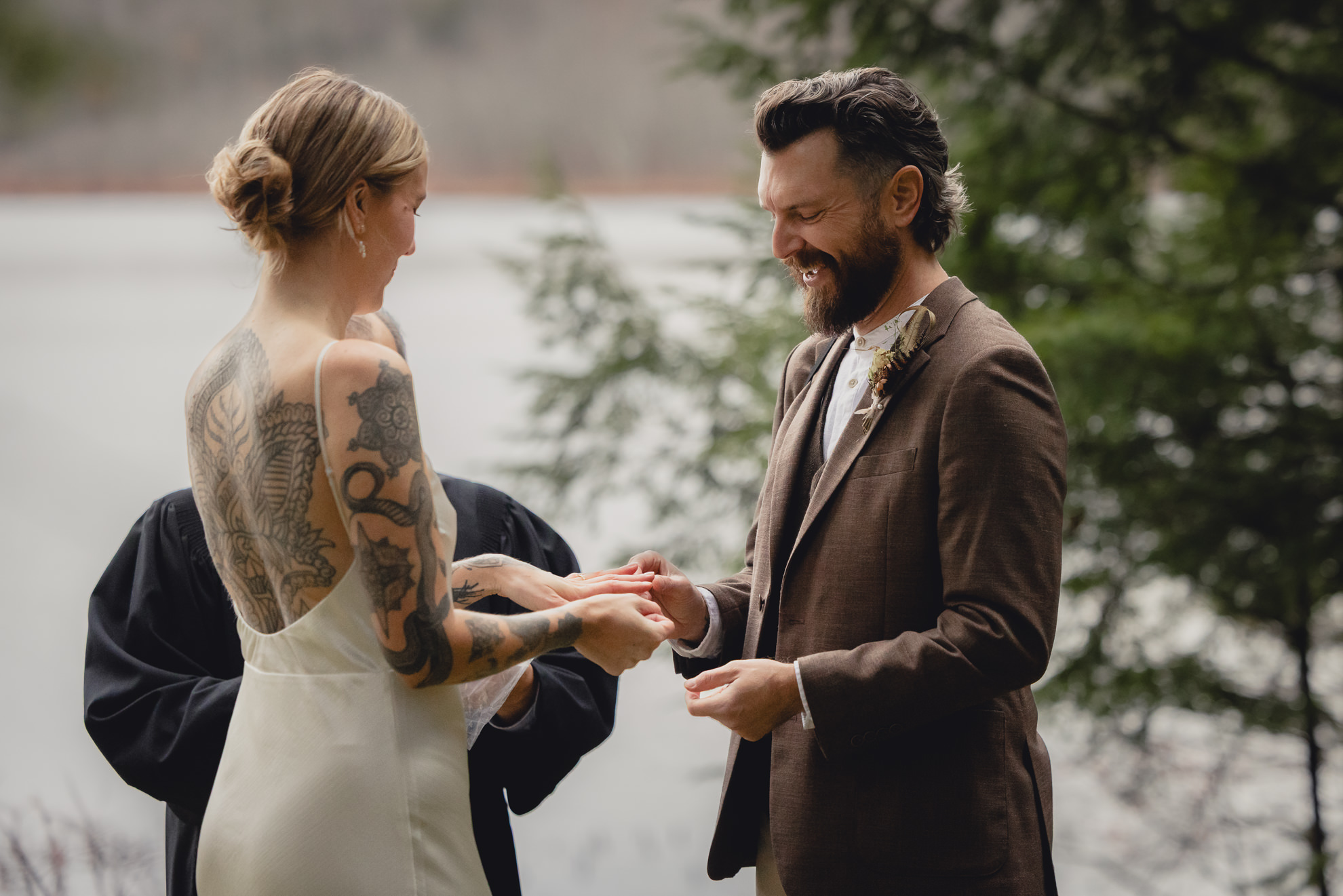 groom smiles as he places ring on brides hand during micro wedding elopement ceremony at Vanderkamp NY in the Adirondacks