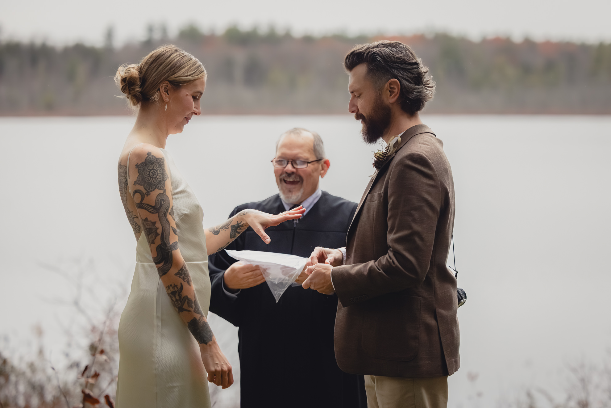 bride looks at ring on hand in front of lake during micro wedding elopement ceremony at Vanderkamp NY in the Adirondacks