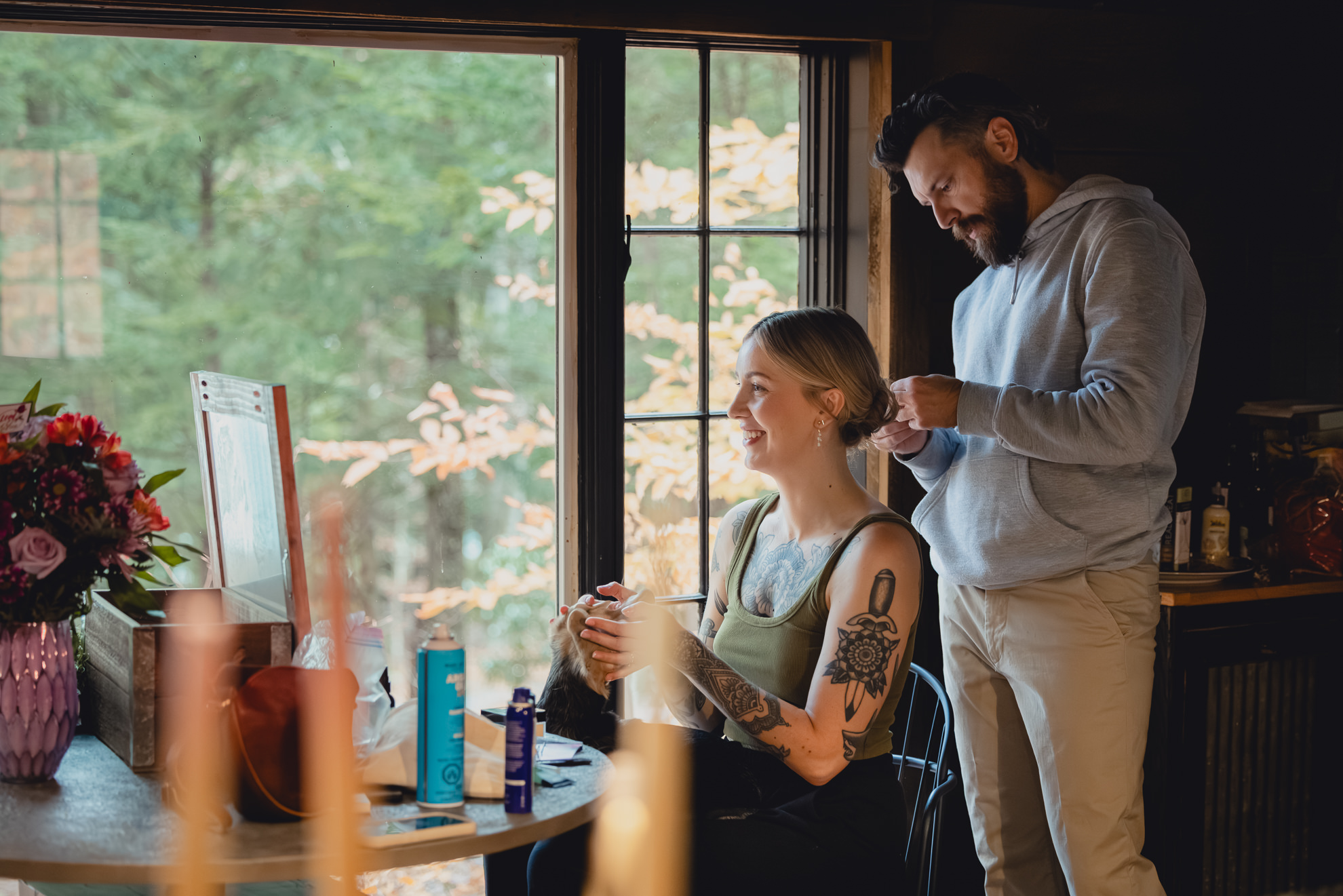 groom helps bride with hair at Langston Cottage at Vanderkamp NY before wedding elopement in the Adirondacks