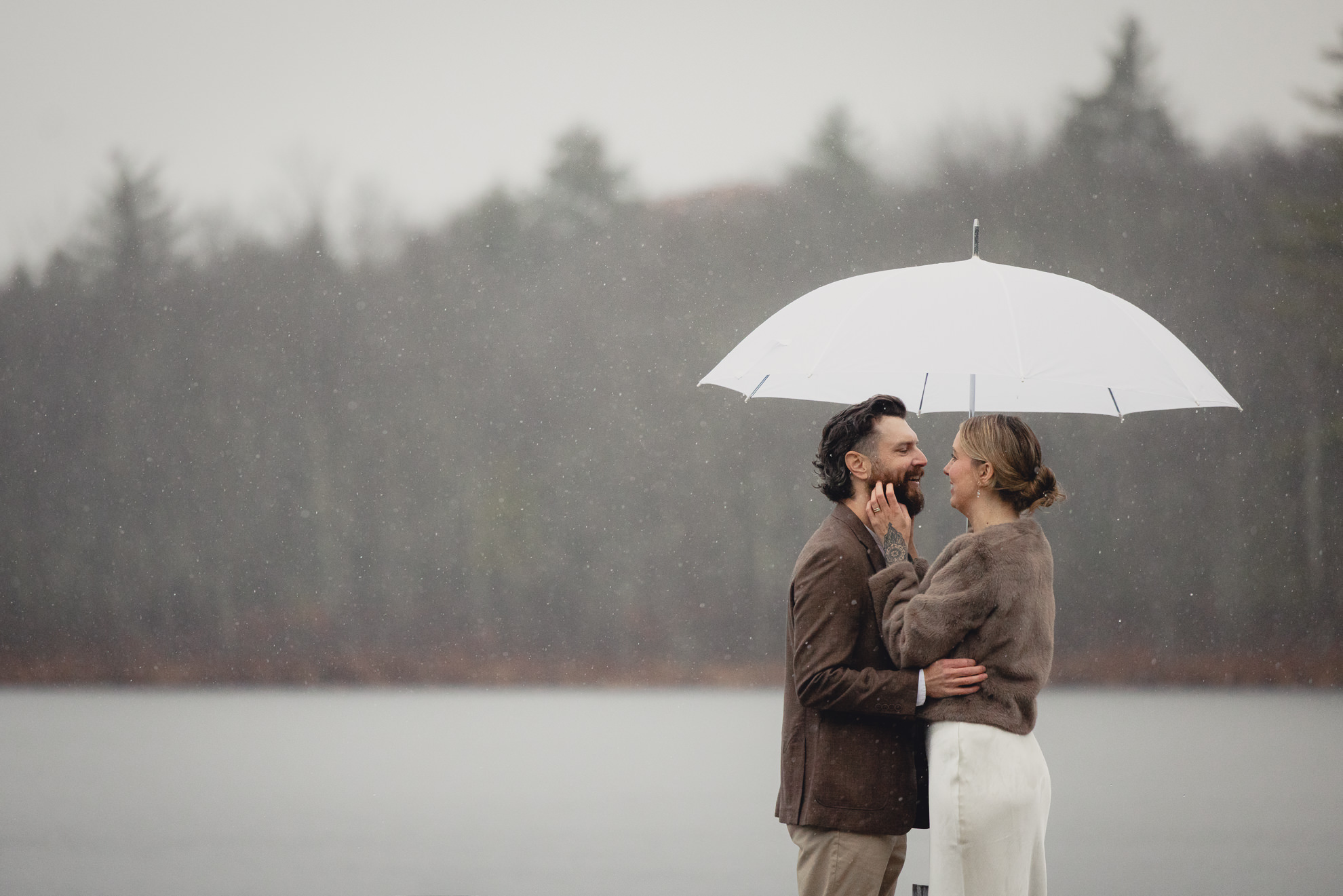 bride and groom laugh with umbrella at lake during fall after micro wedding elopement ceremony at Vanderkamp NY in the Adirondacks