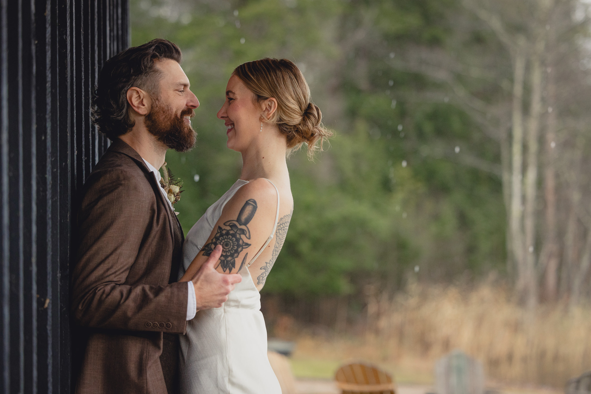 bride and groom look at each other under shelter by lake during fall after micro wedding elopement ceremony at Vanderkamp NY in the Adirondacks