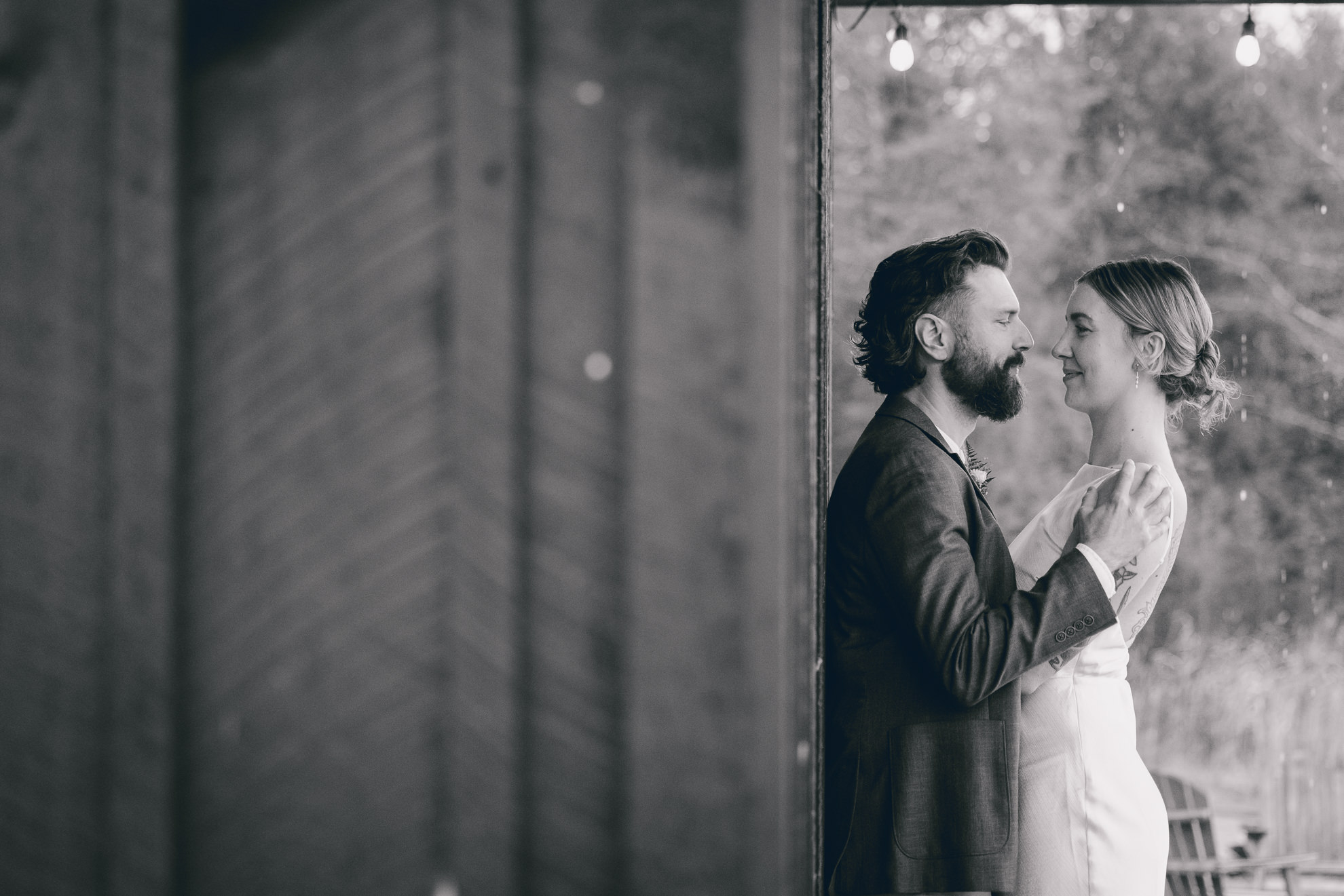 bride and groom look at each other under shelter by lake during fall after micro wedding elopement ceremony at Vanderkamp NY in the Adirondacks
