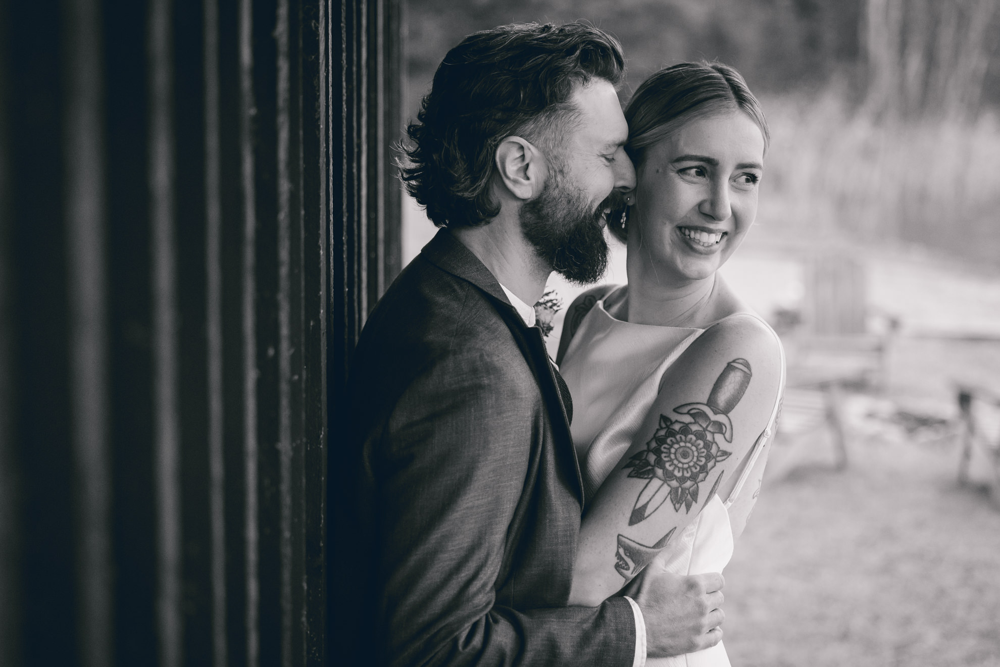bride and groom laugh together under shelter by lake during fall after micro wedding elopement ceremony at Vanderkamp NY in the Adirondacks